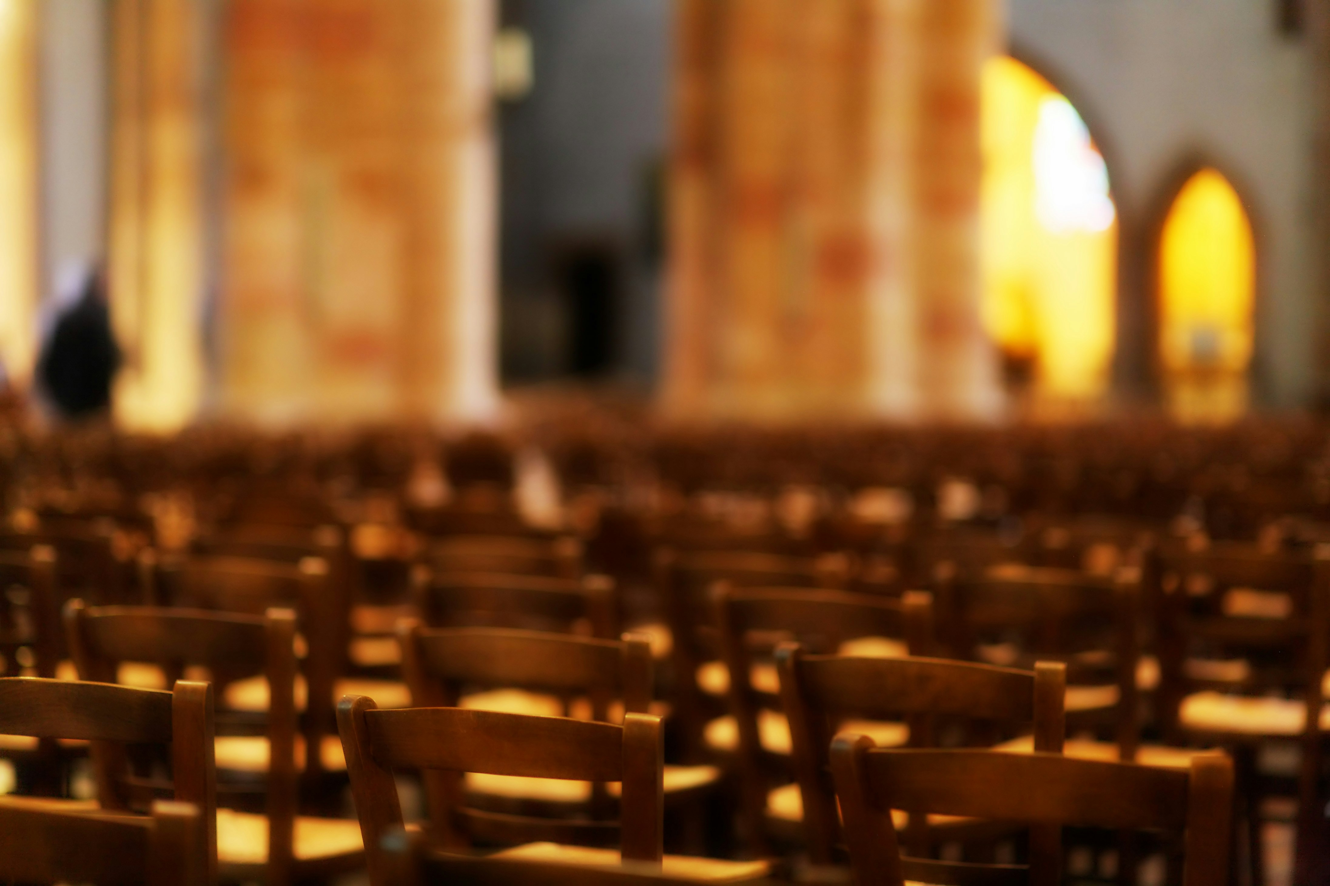 Rows of empty wooden chairs in a large hall.