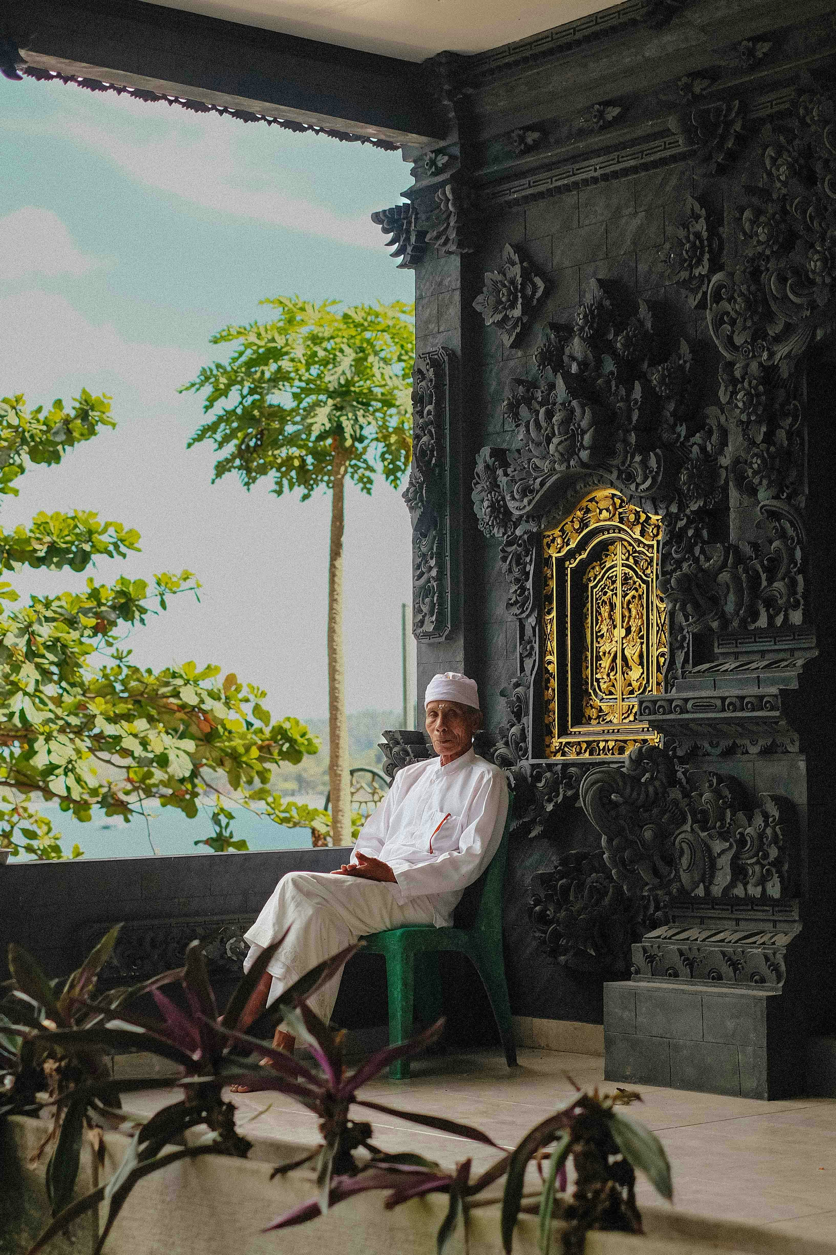 Man in white traditional clothing sits on a chair.