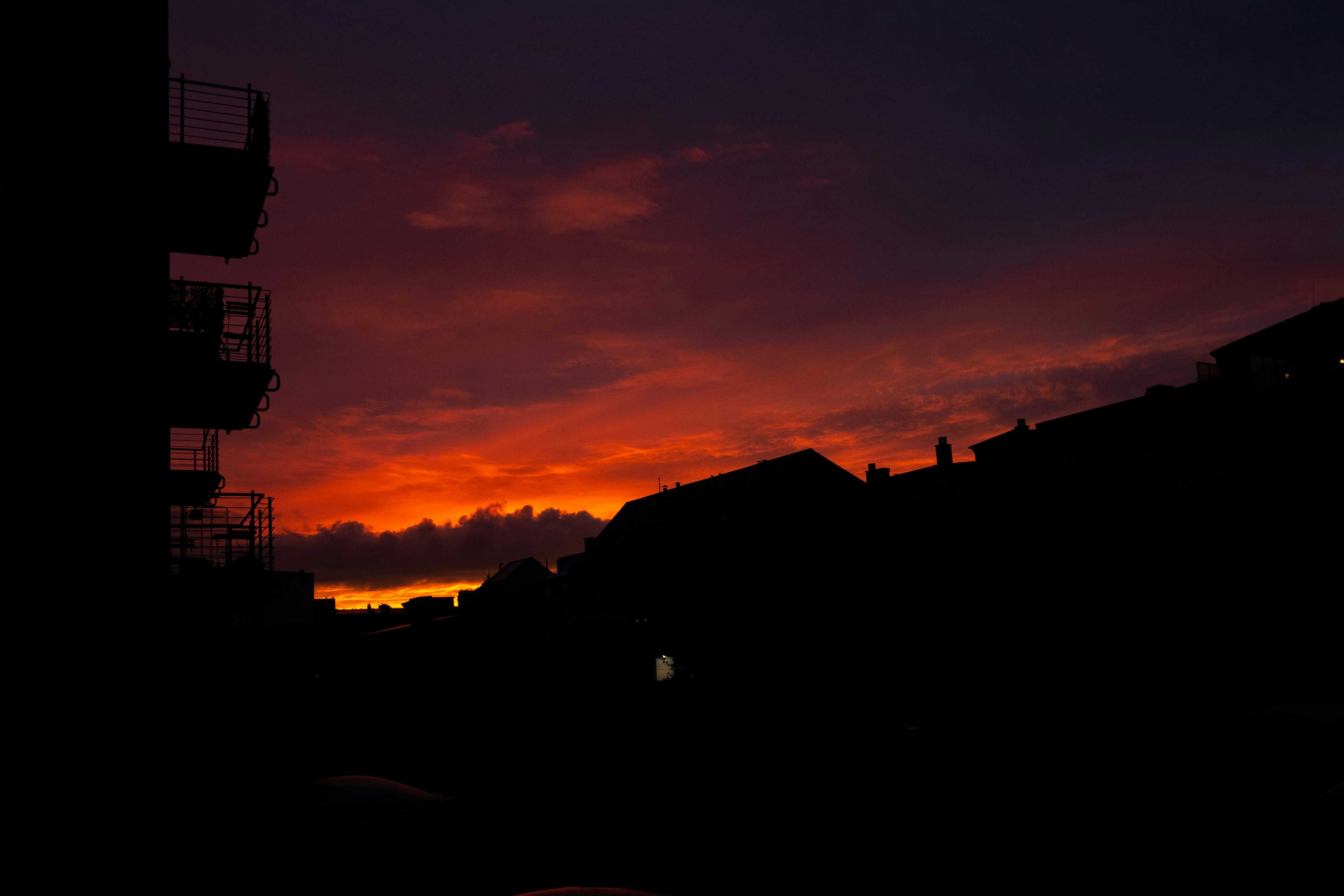 Dramatic sunset over silhouetted buildings and darkened buildings.
