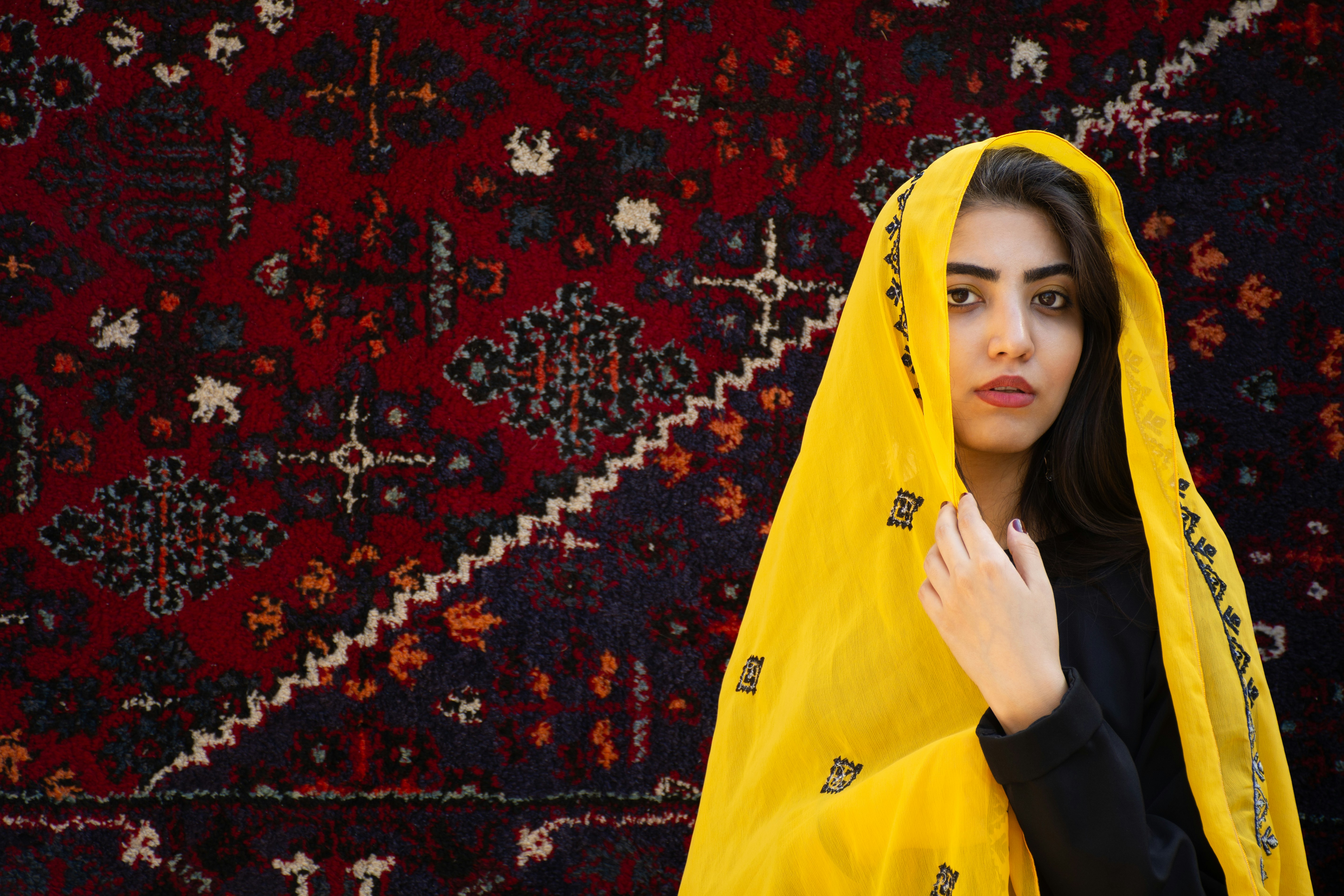Young woman in yellow veil against patterned rug
