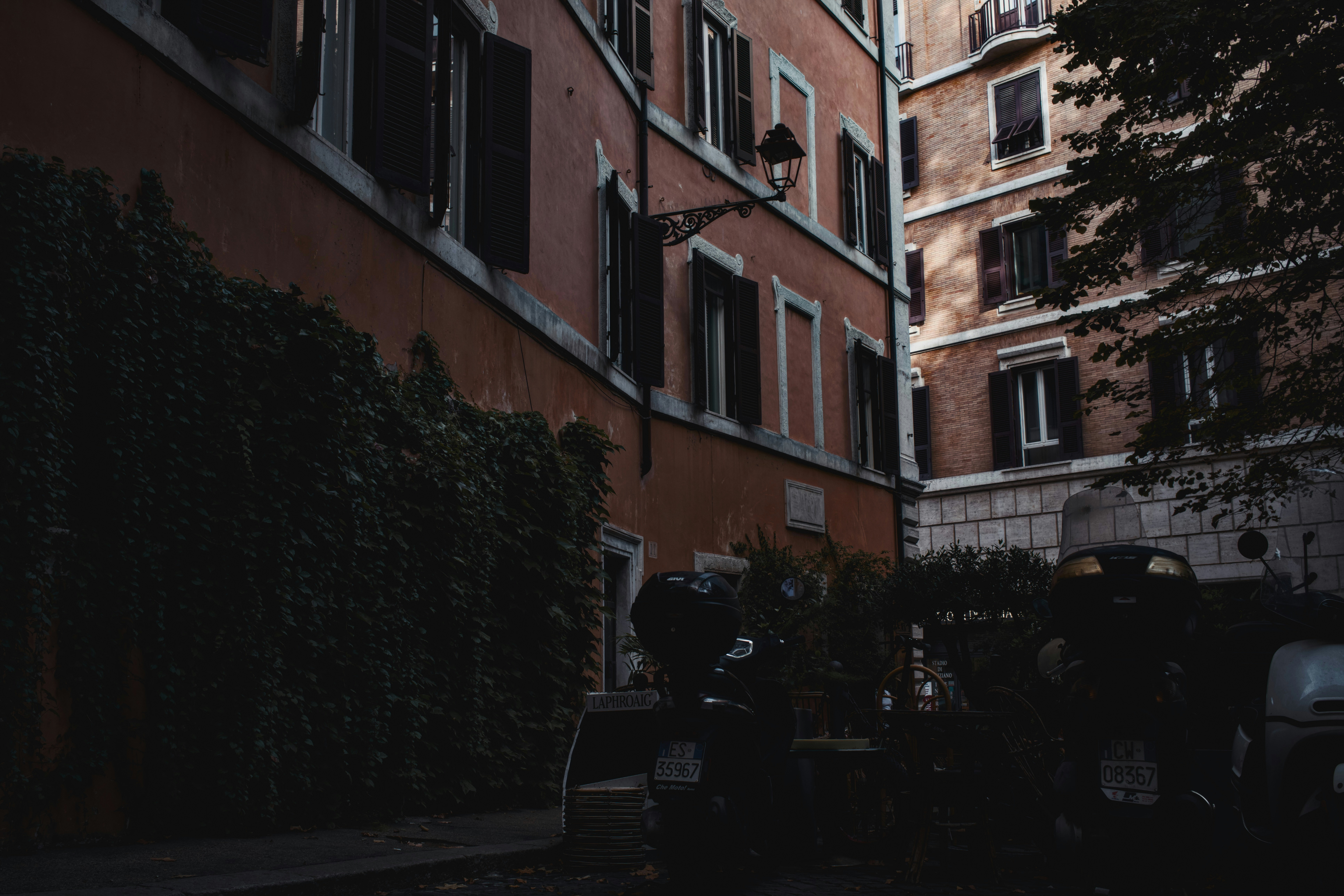 Buildings with ivy and parked scooters in alley.