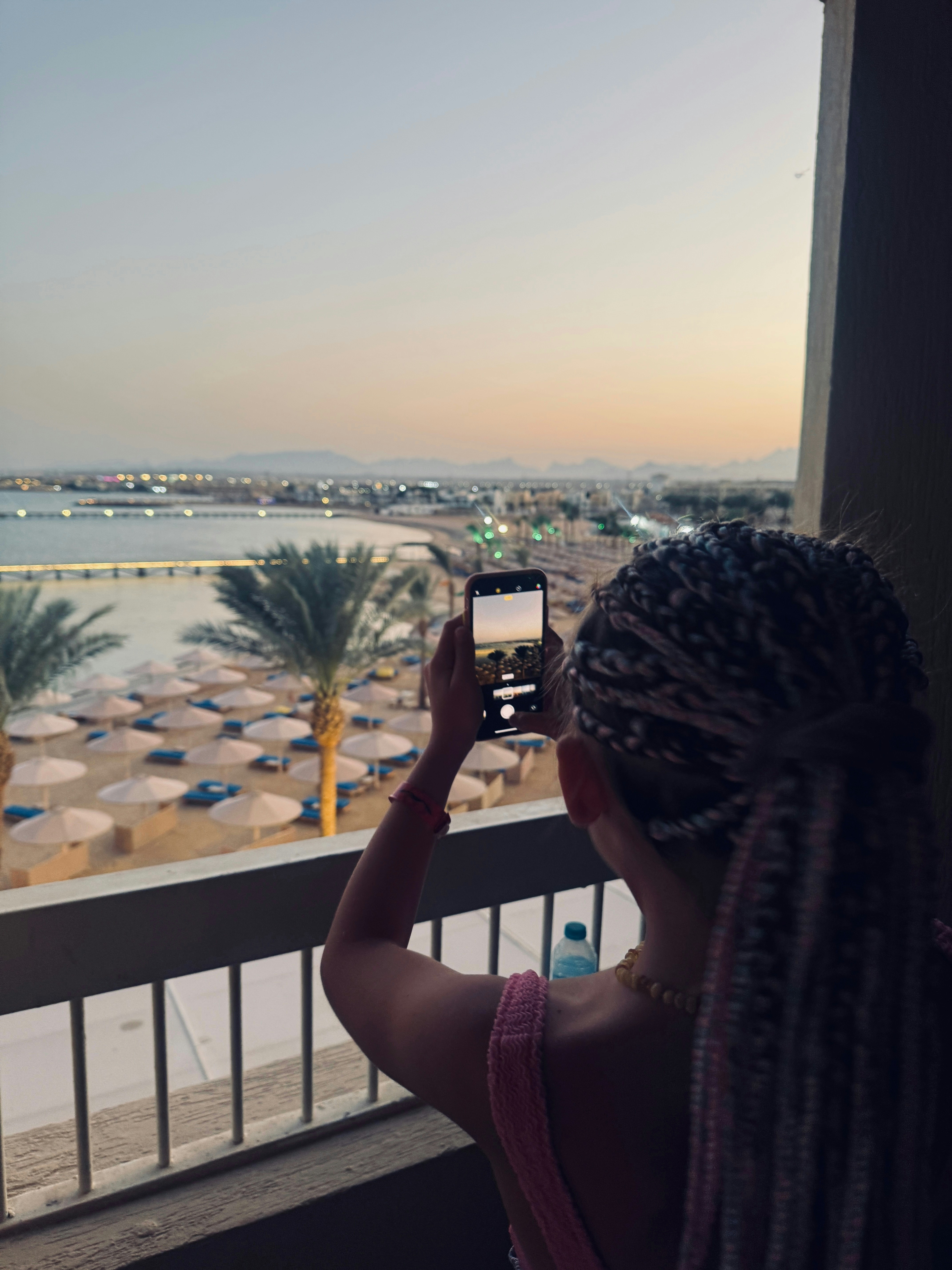 Woman takes a picture of beach sunset with phone