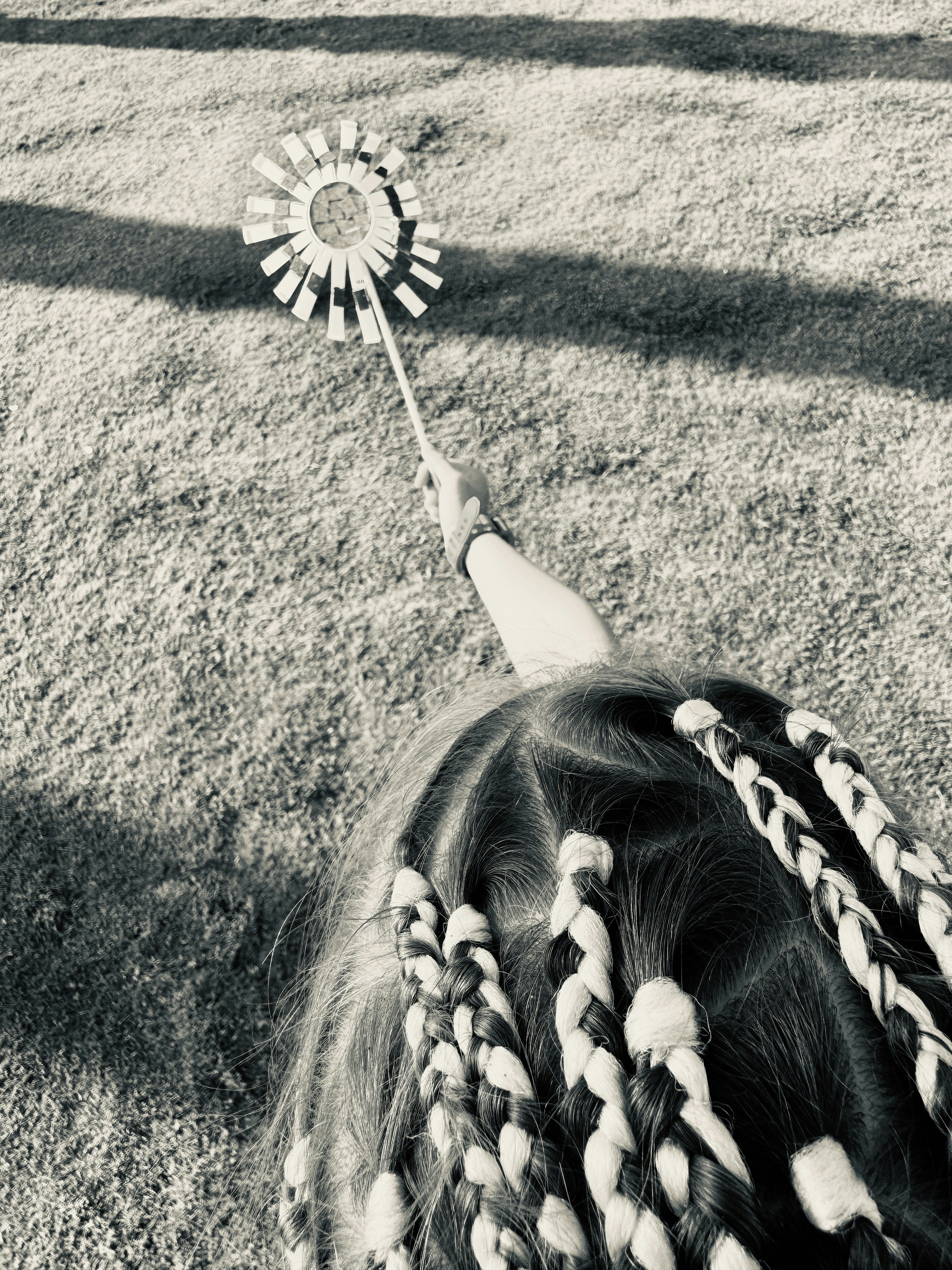 Child with braided hair holds a pinwheel outdoors
