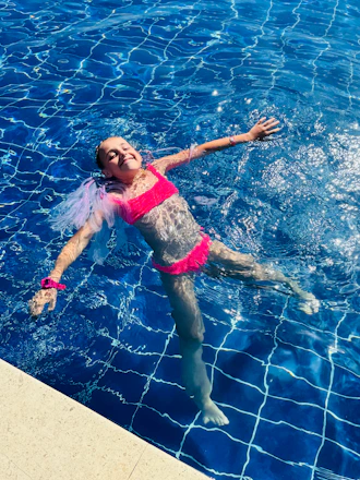 A happy girl floats on her back in a pool.