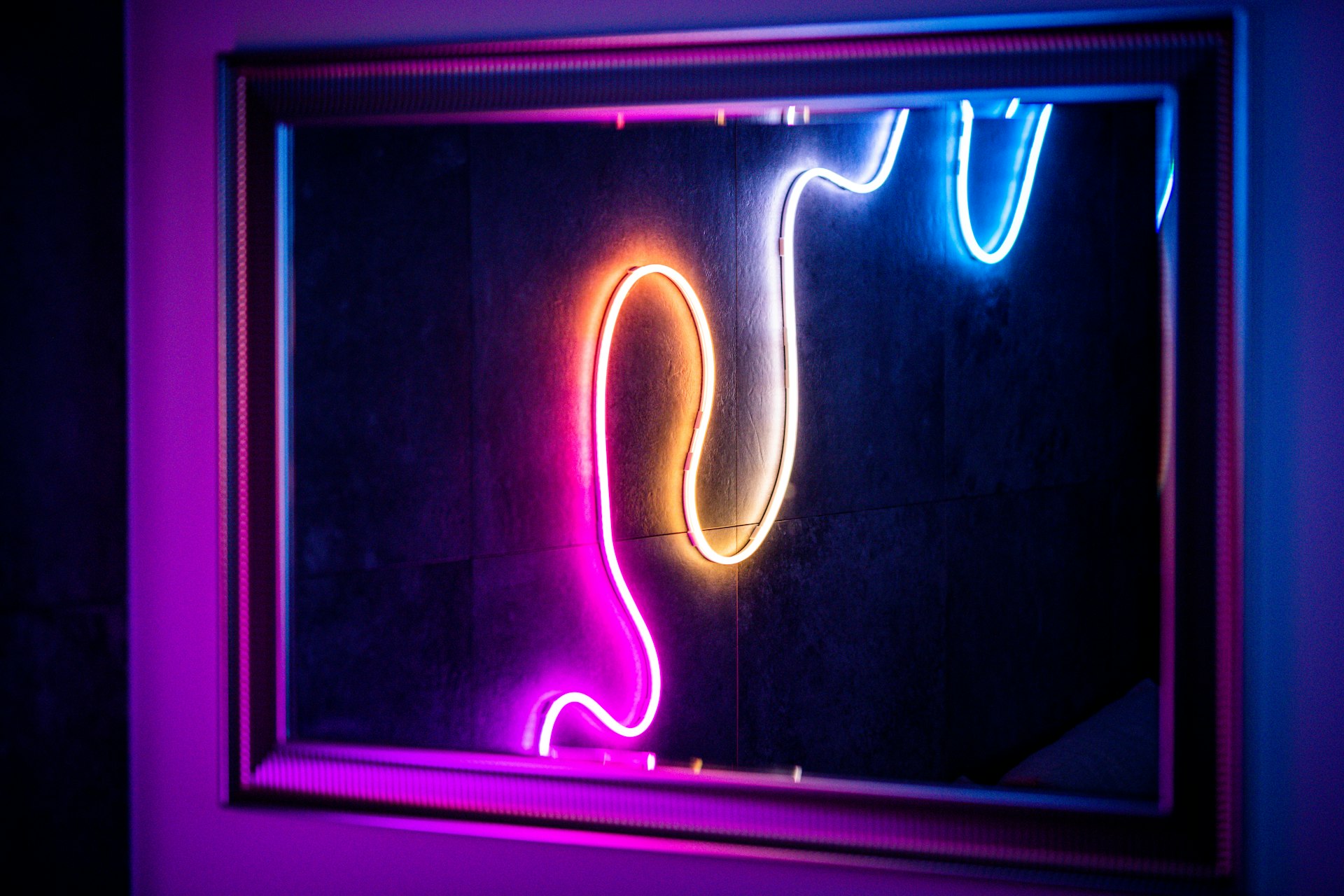 Neon lights reflected in a framed mirror