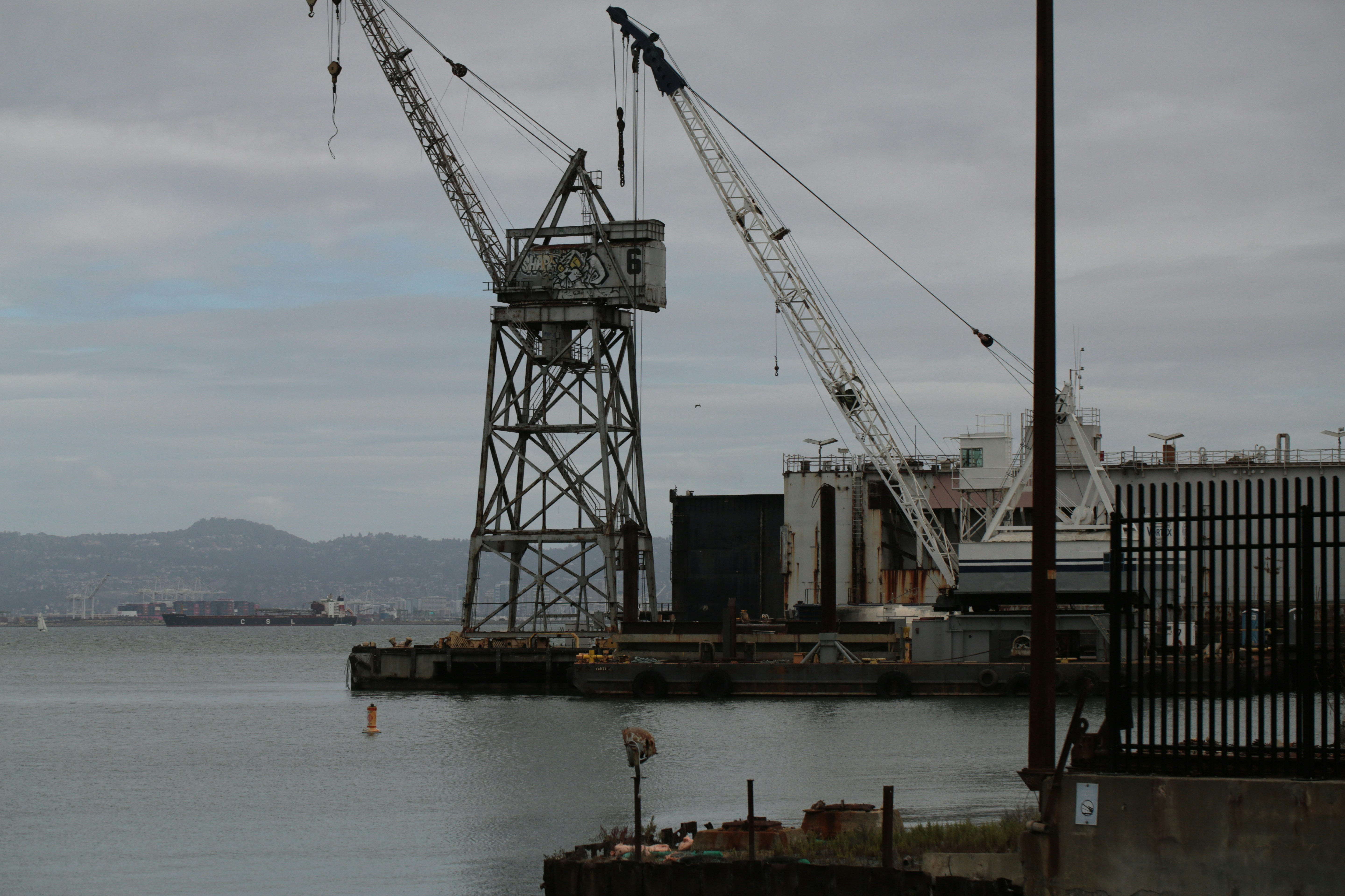 Two large cranes stand by the water's edge.