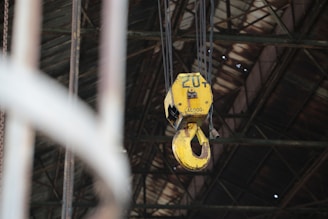 Yellow industrial crane hook hangs from ceiling