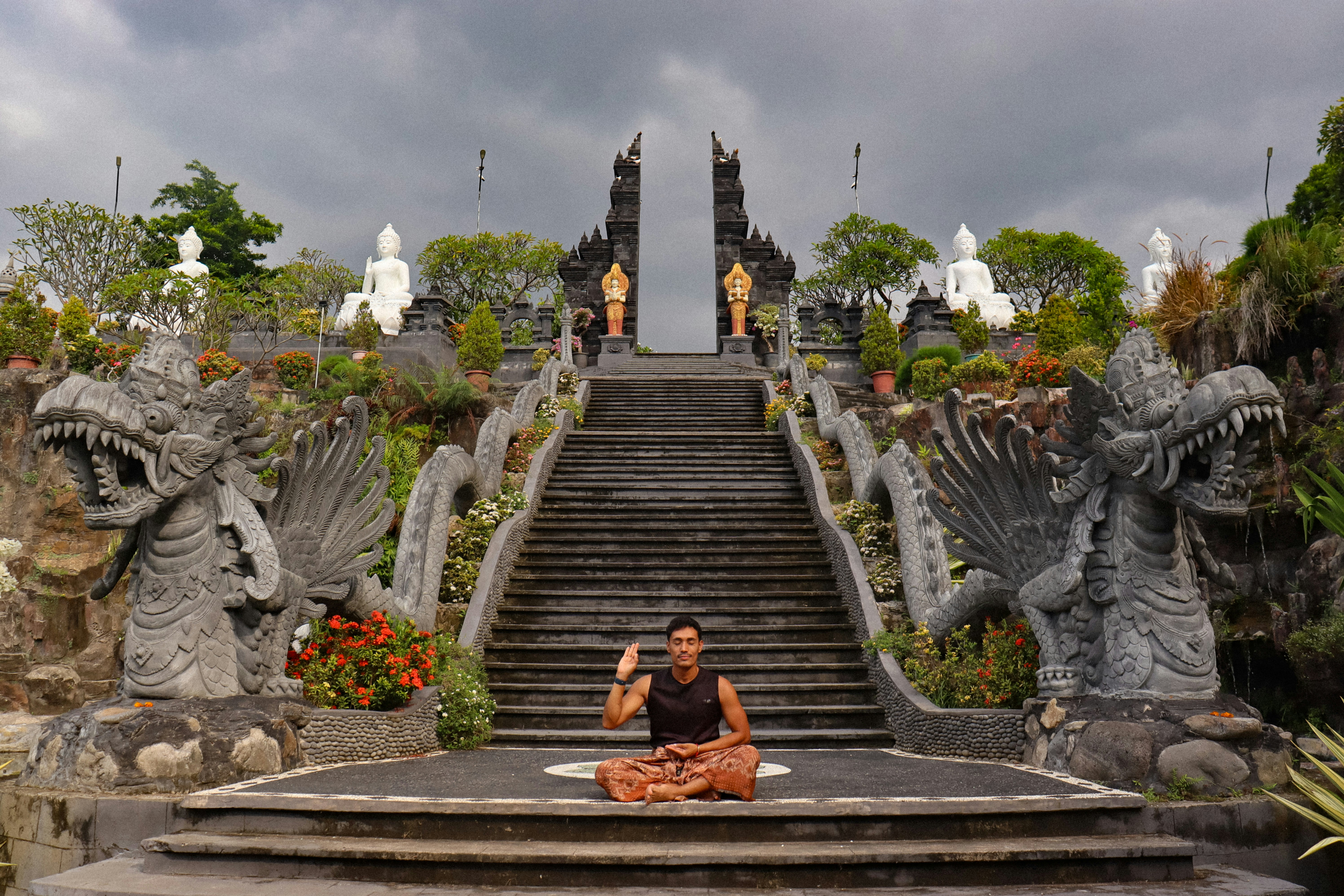 Man meditating at temple entrance with dragon statues