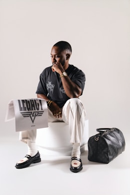 Man in stylish outfit holding a towel with logo.