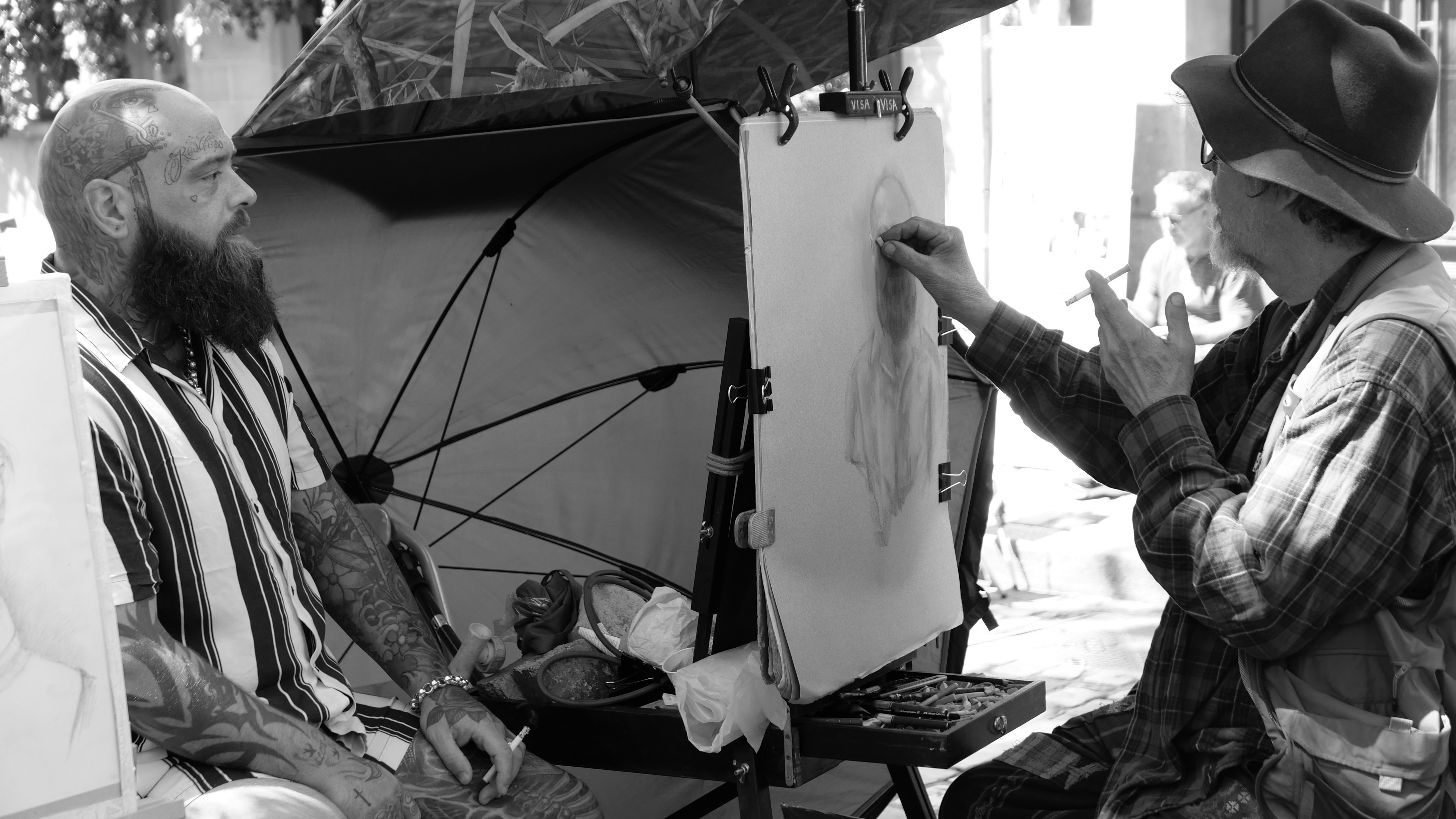 Artist sketching a man sitting under an umbrella