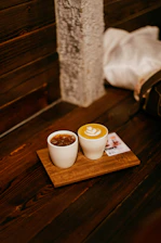 Two coffee drinks on a wooden tray
