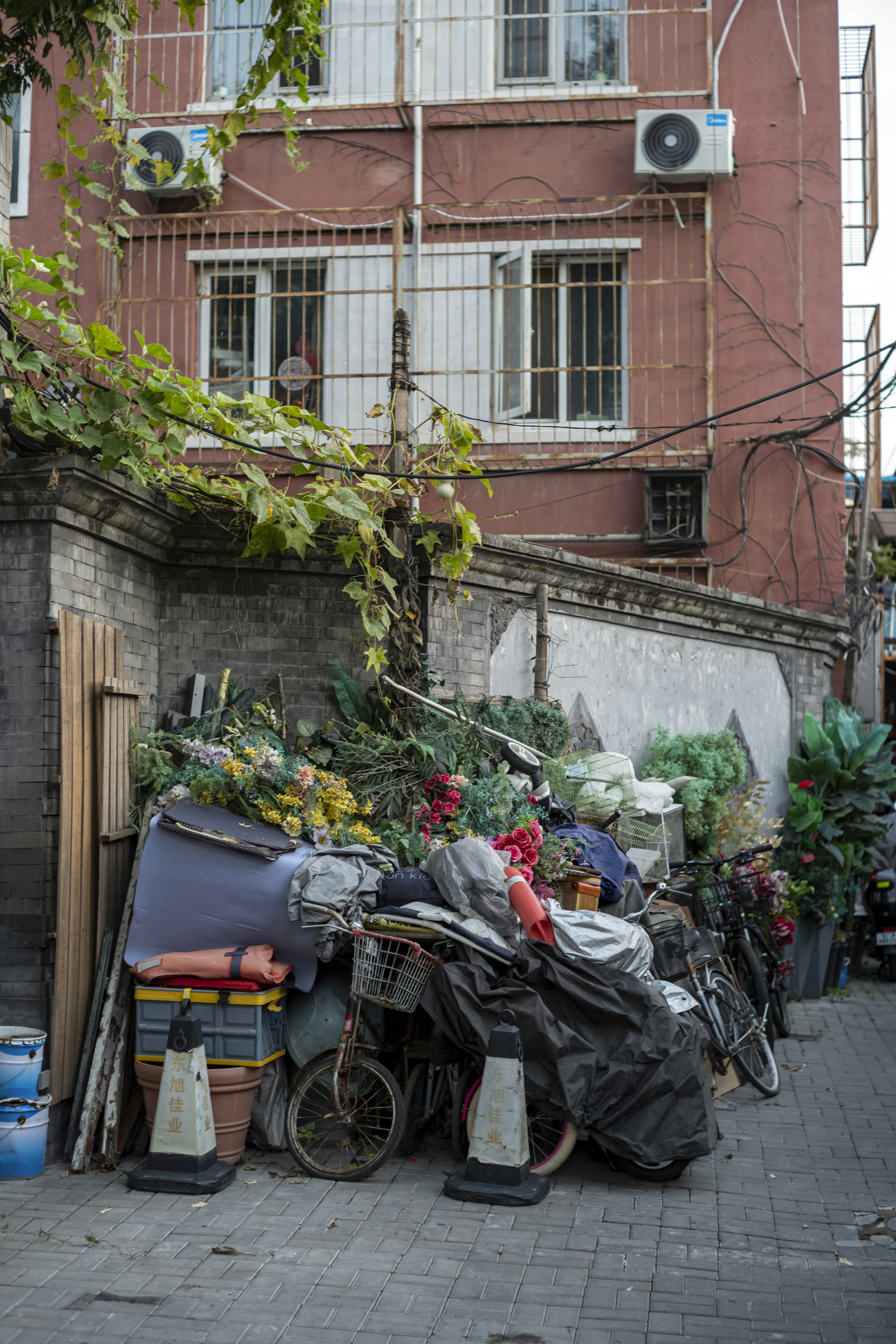 Cluttered alleyway with piled-up belongings and bicycles.