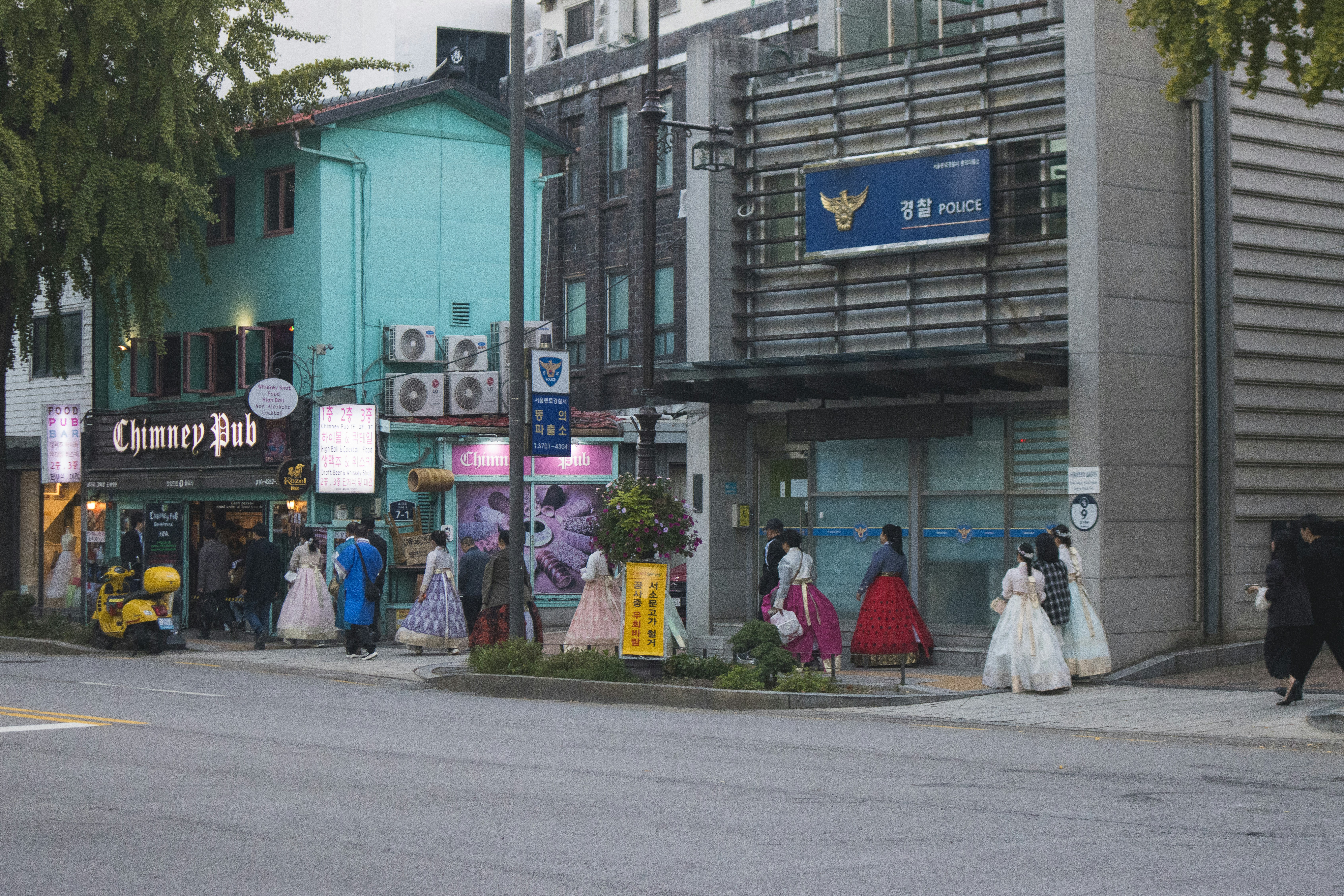 People in traditional korean hanbok walk on a street.