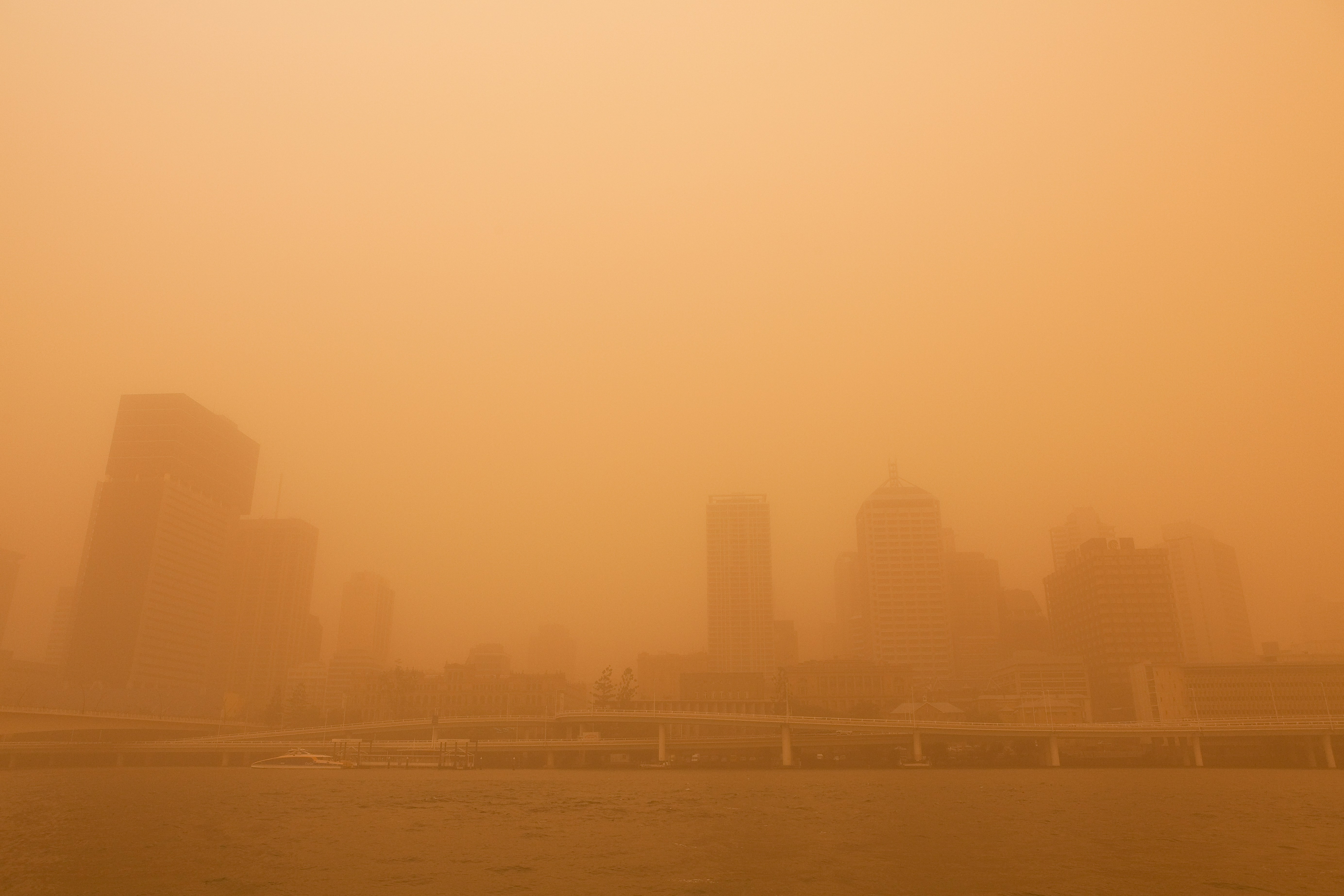 City skyline obscured by a thick orange dust storm.
