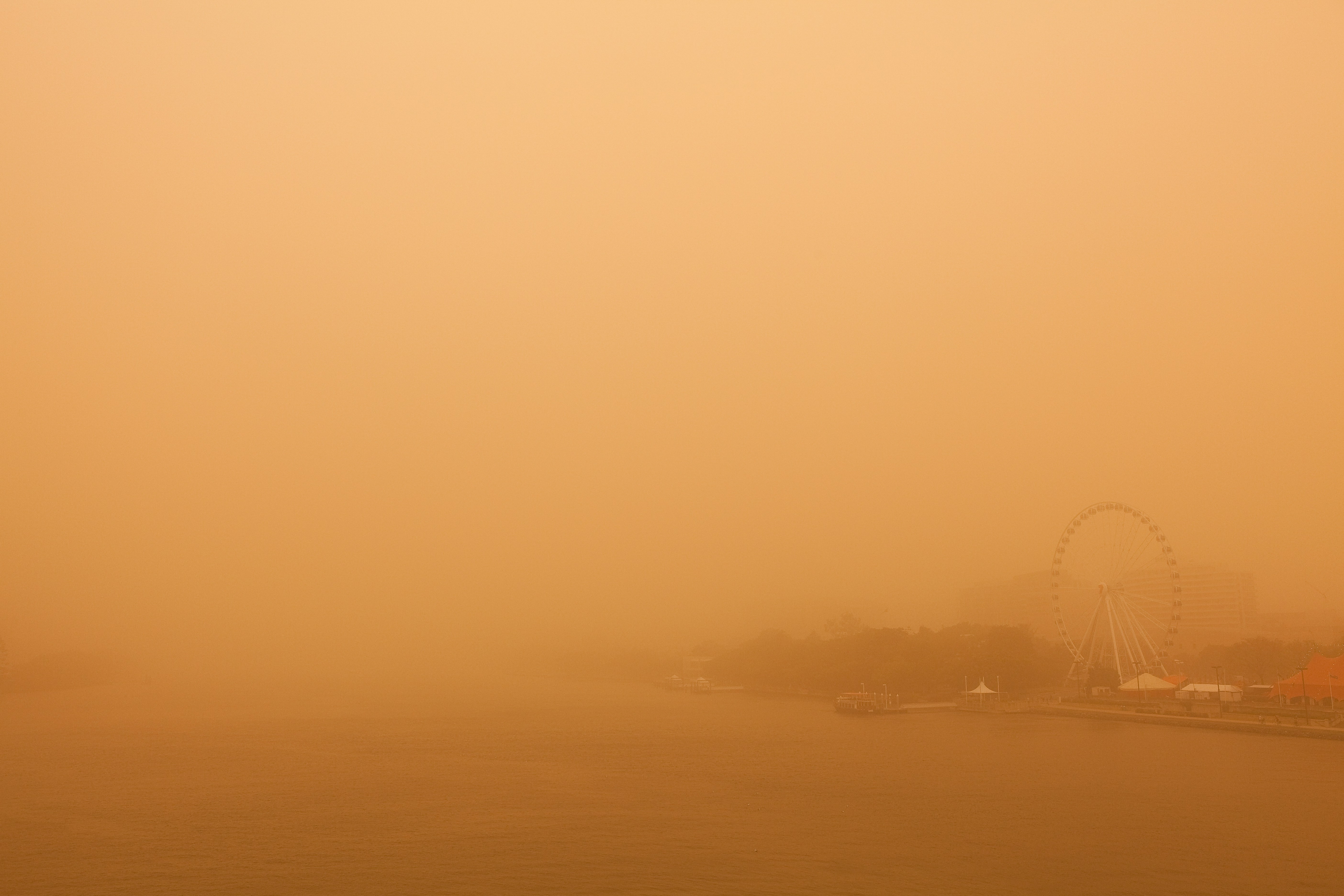 Dust storm obscures city skyline and ferris wheel.