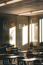Sunlight streams into an empty classroom with desks.