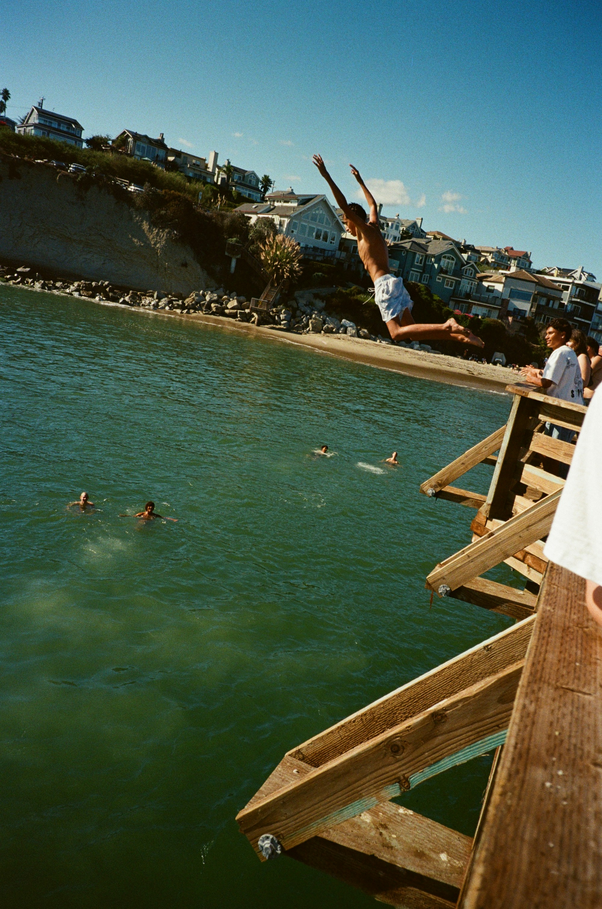 Person jumps off wooden platform into ocean