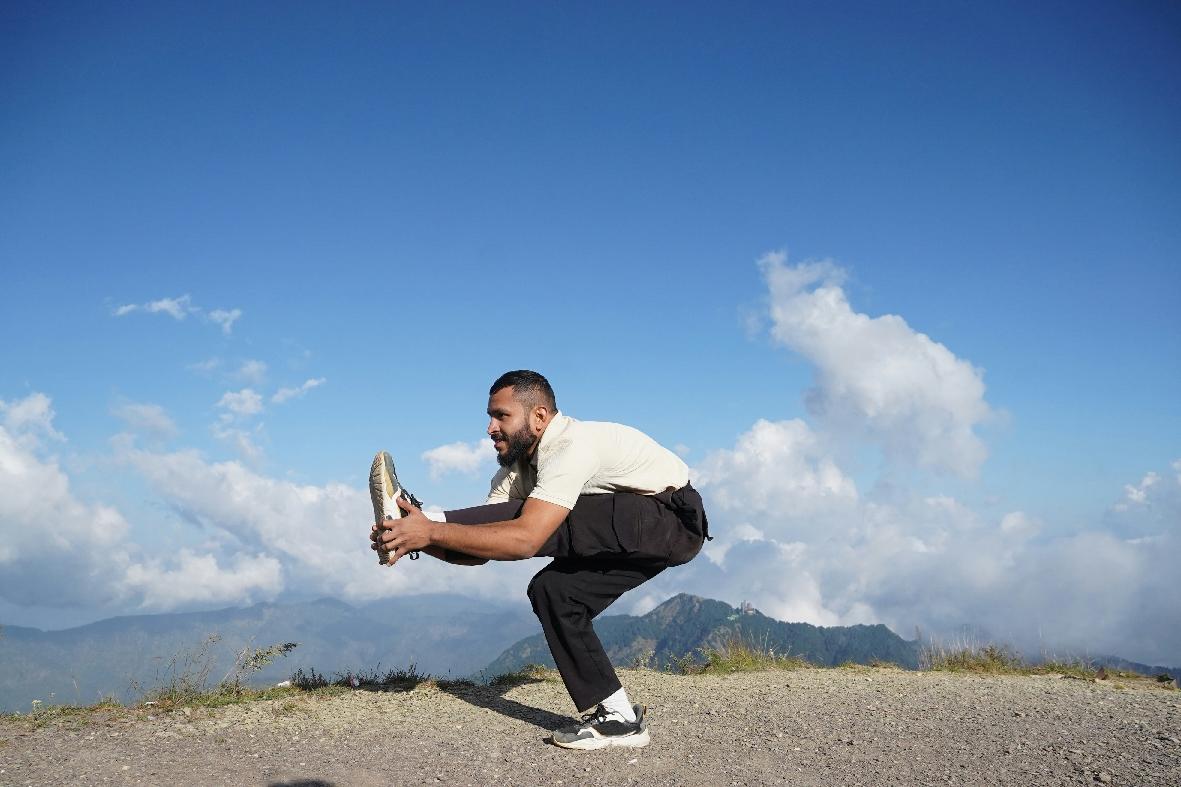 Man doing yoga pose on a mountain top.