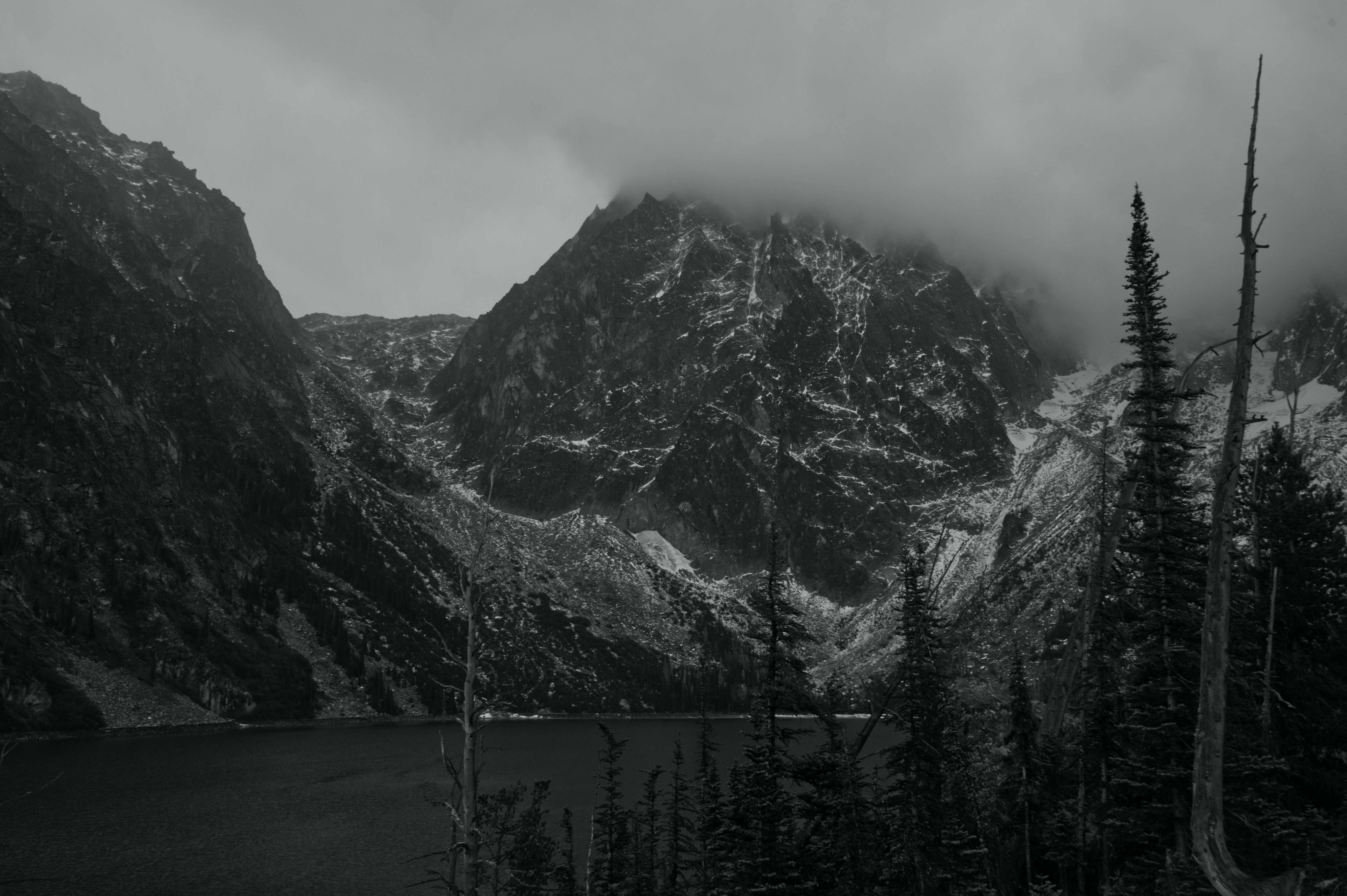 Pico de montaña cubierto de nieve con un lago debajo.