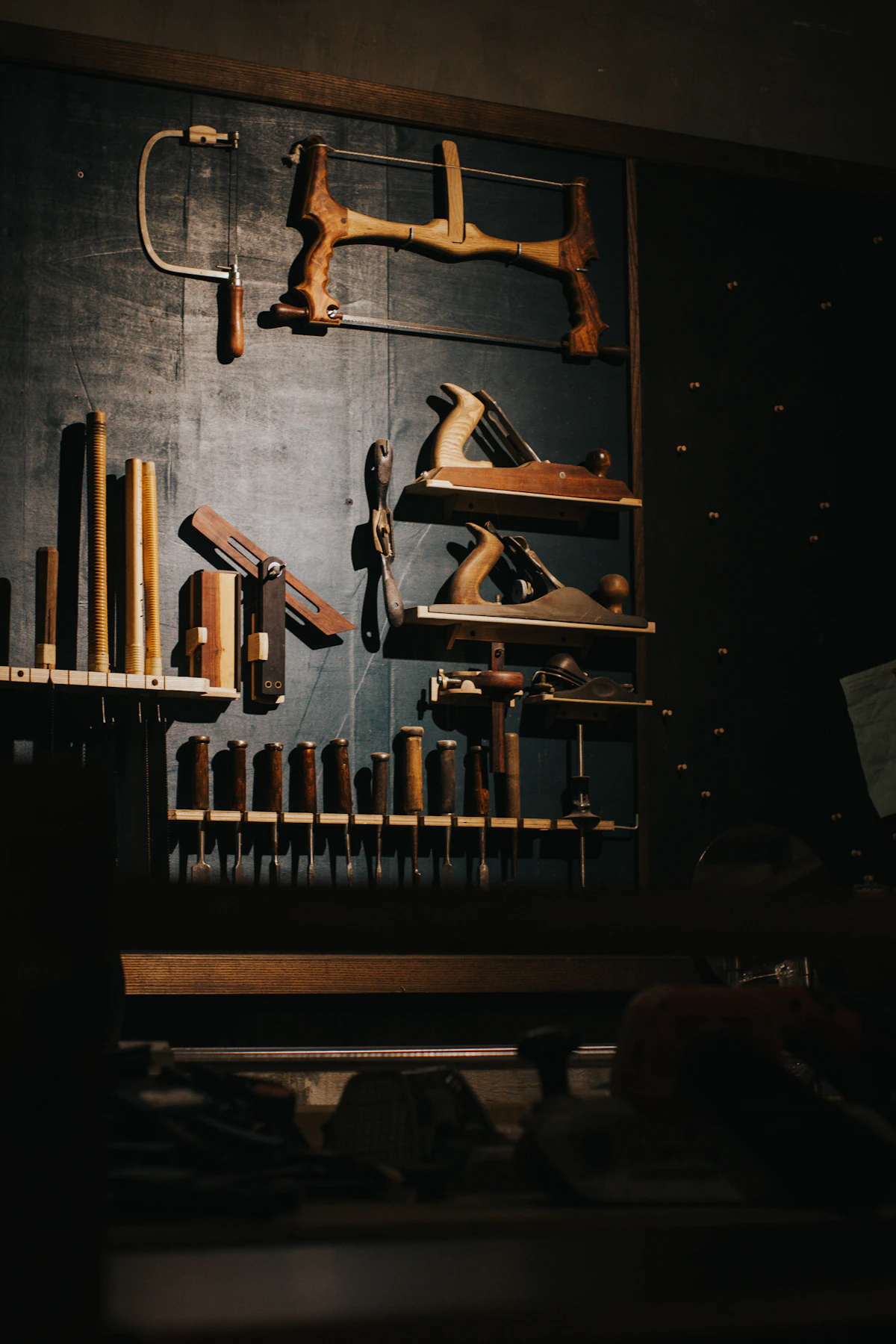 Vintage woodworking hand tools arranged on a dark wall
