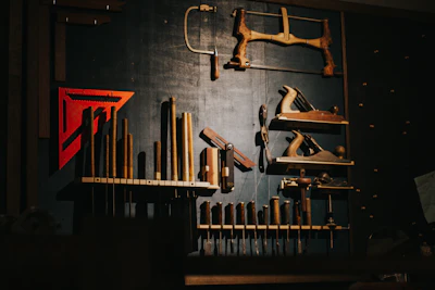 Various woodworking tools hang on a dark wall.