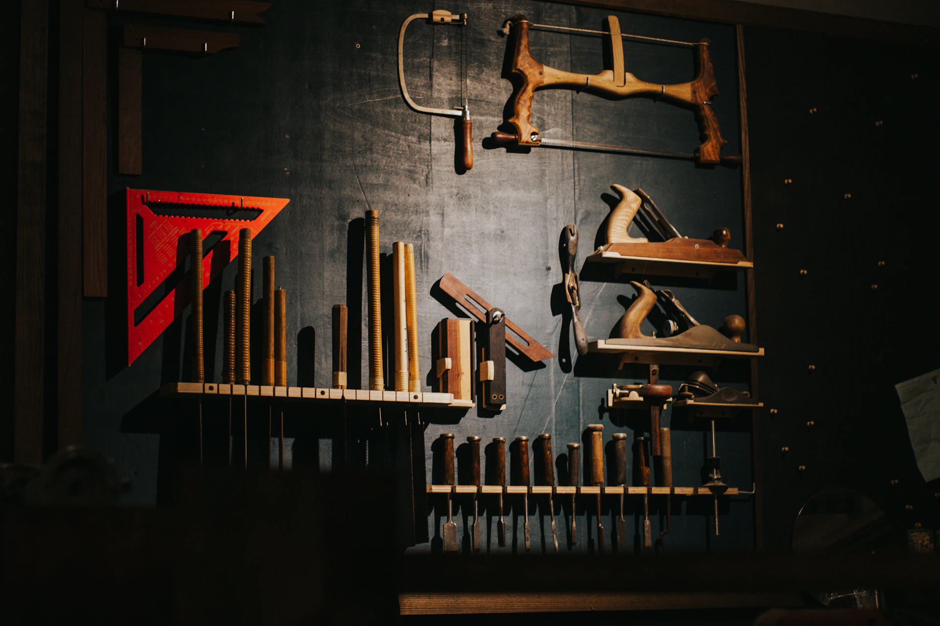 Various woodworking tools hang on a dark wall.
