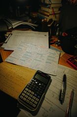 Desk with calculator, pens, and study papers