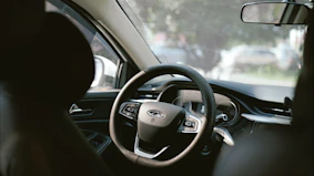 Interior view of a car's steering wheel and dashboard.