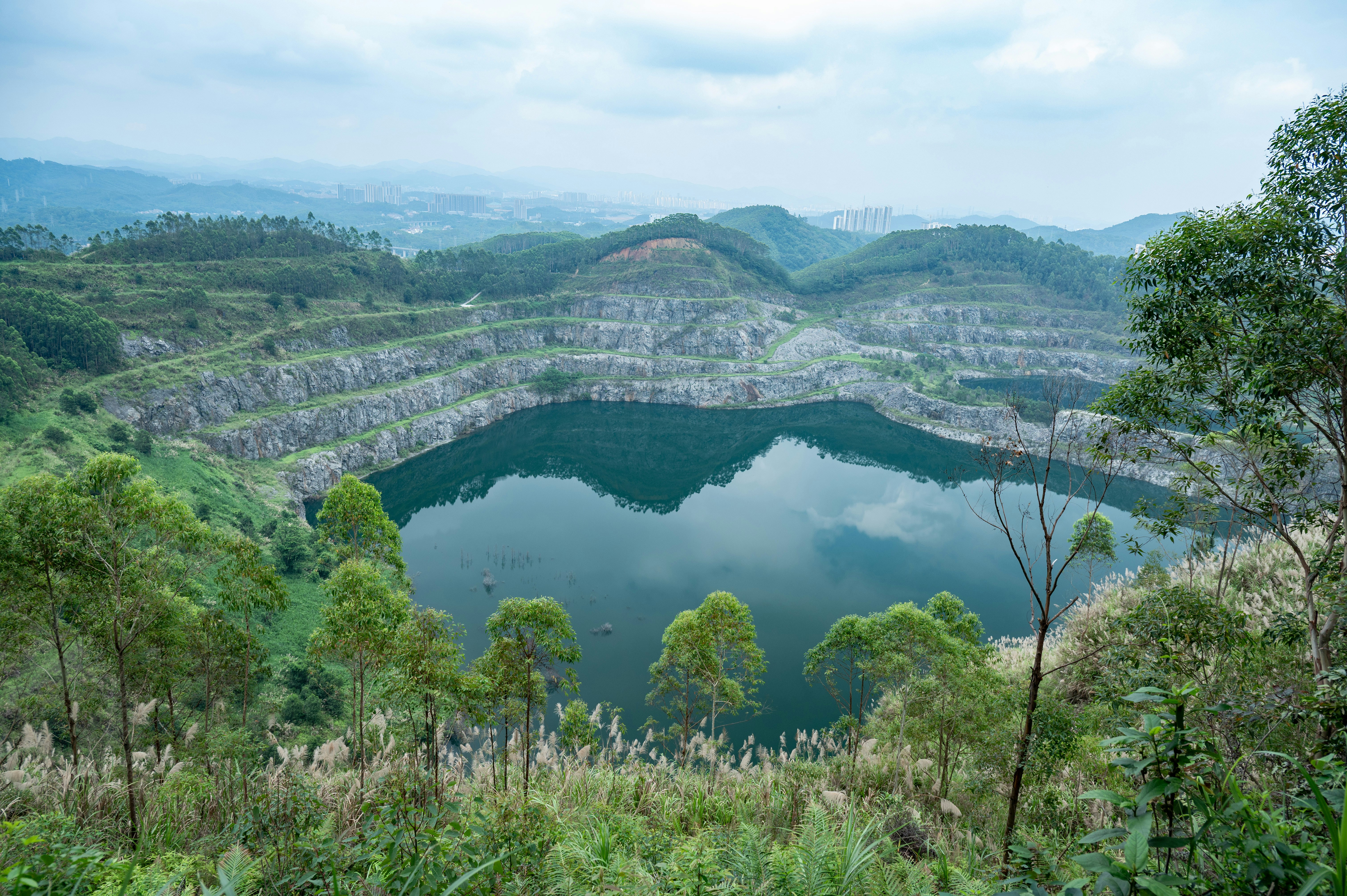 A serene lake fills a large quarry surrounded by trees.