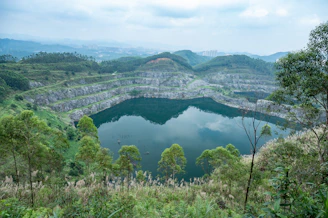 A serene lake fills a large quarry surrounded by trees.