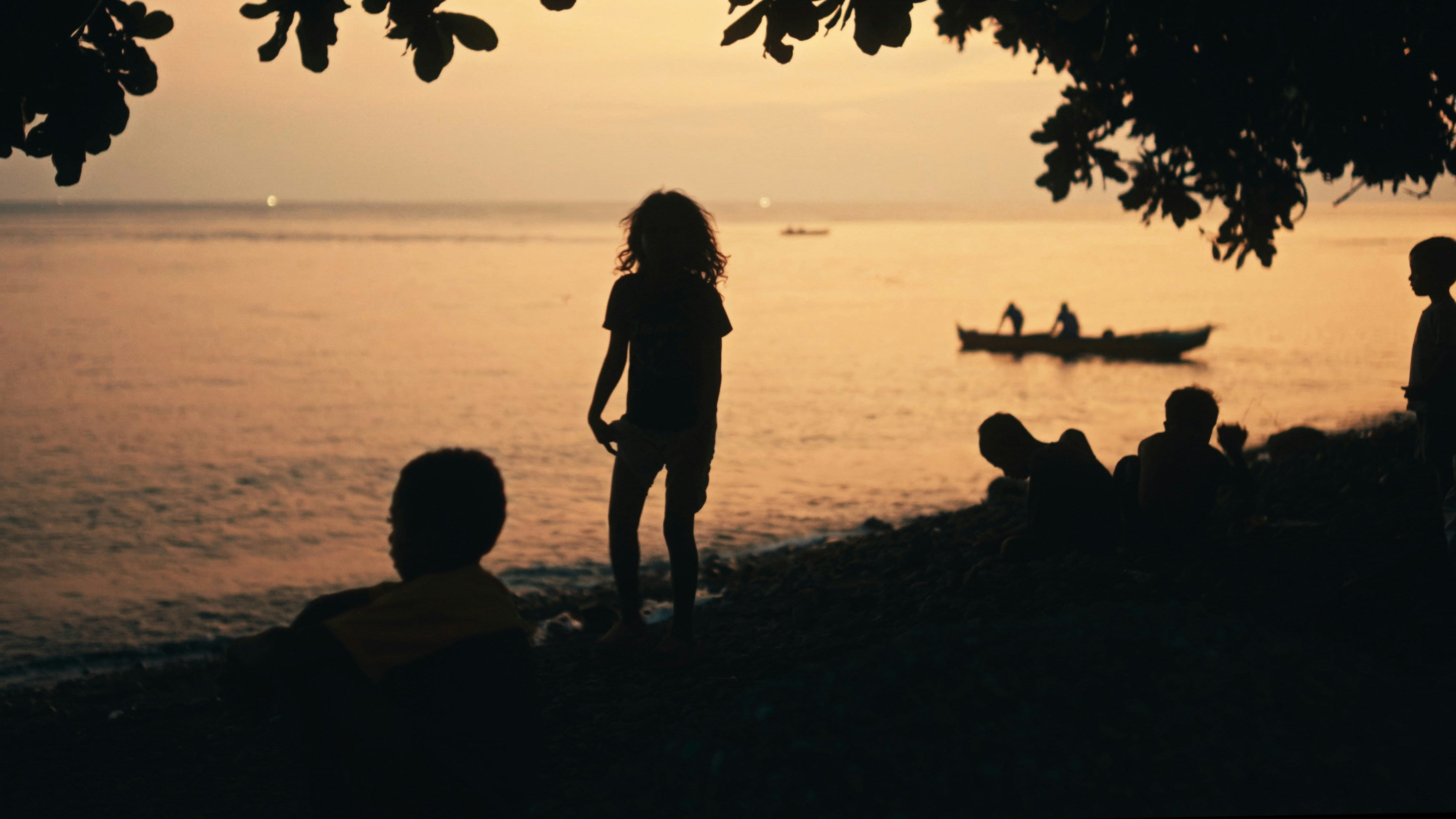 Children silhouetted on a beach at sunset
