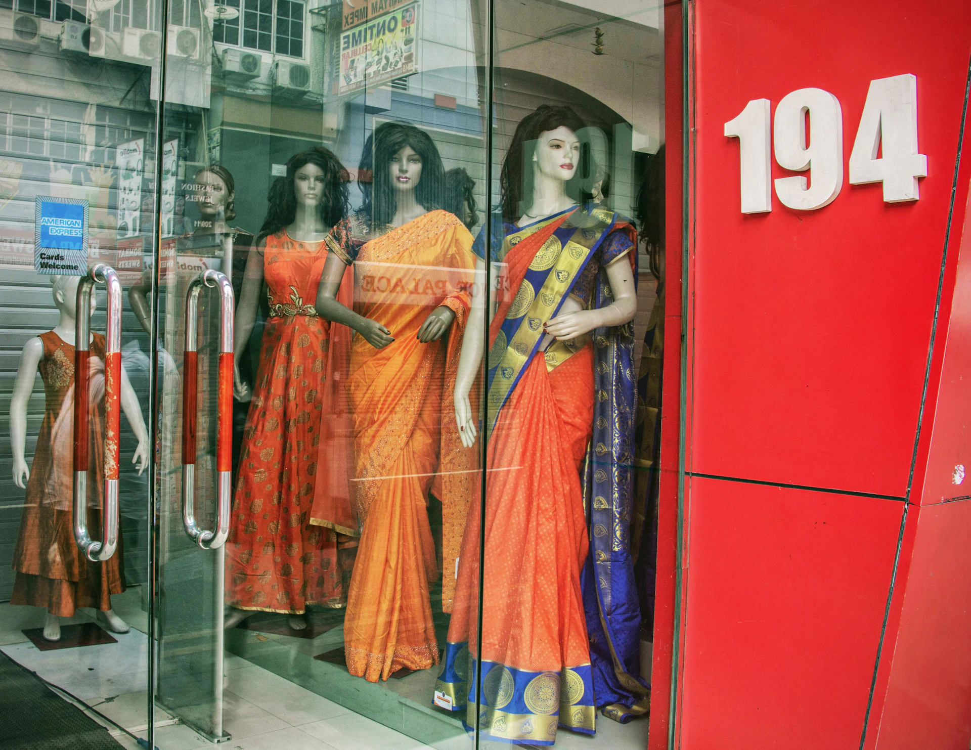 Mannequins in traditional indian saris displayed in store window.