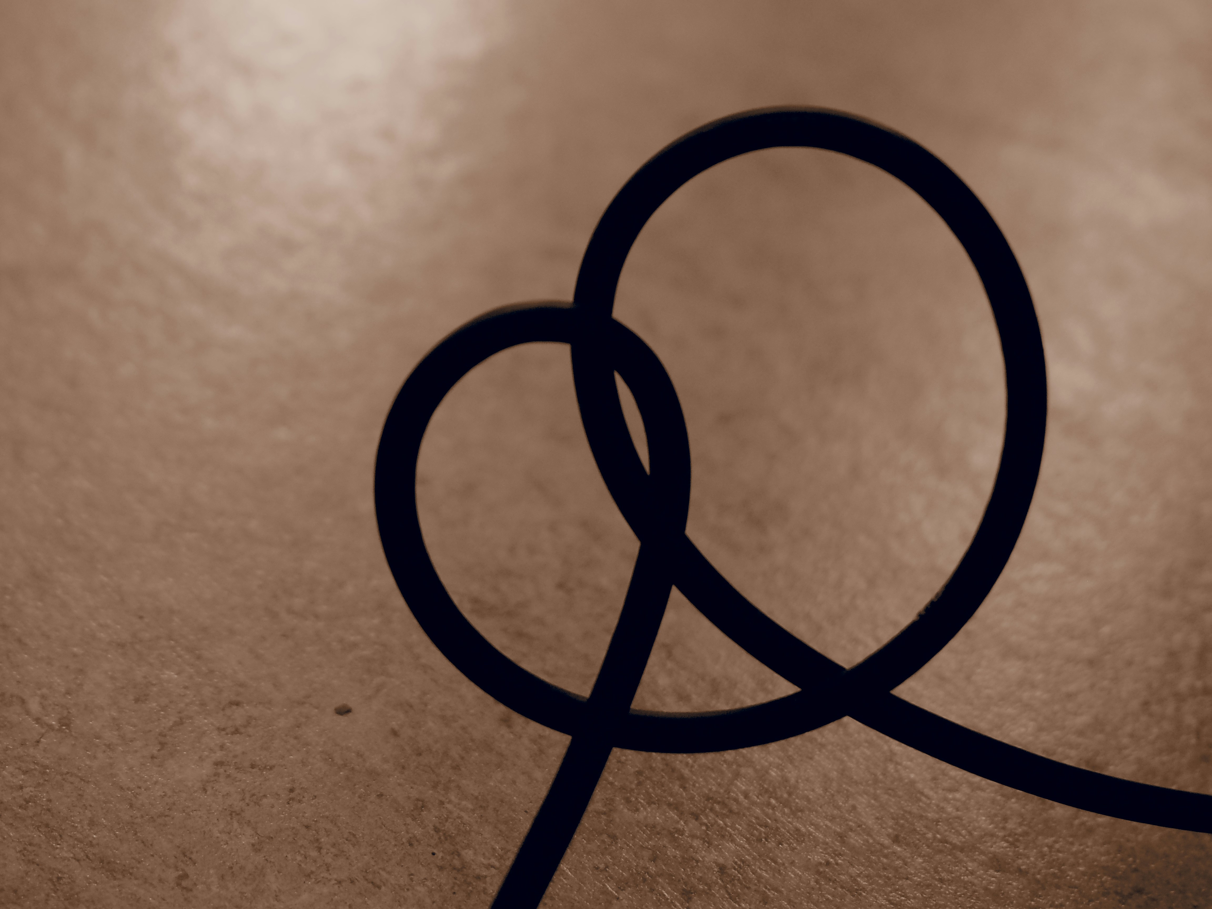 A dark line forms a heart shape on textured background