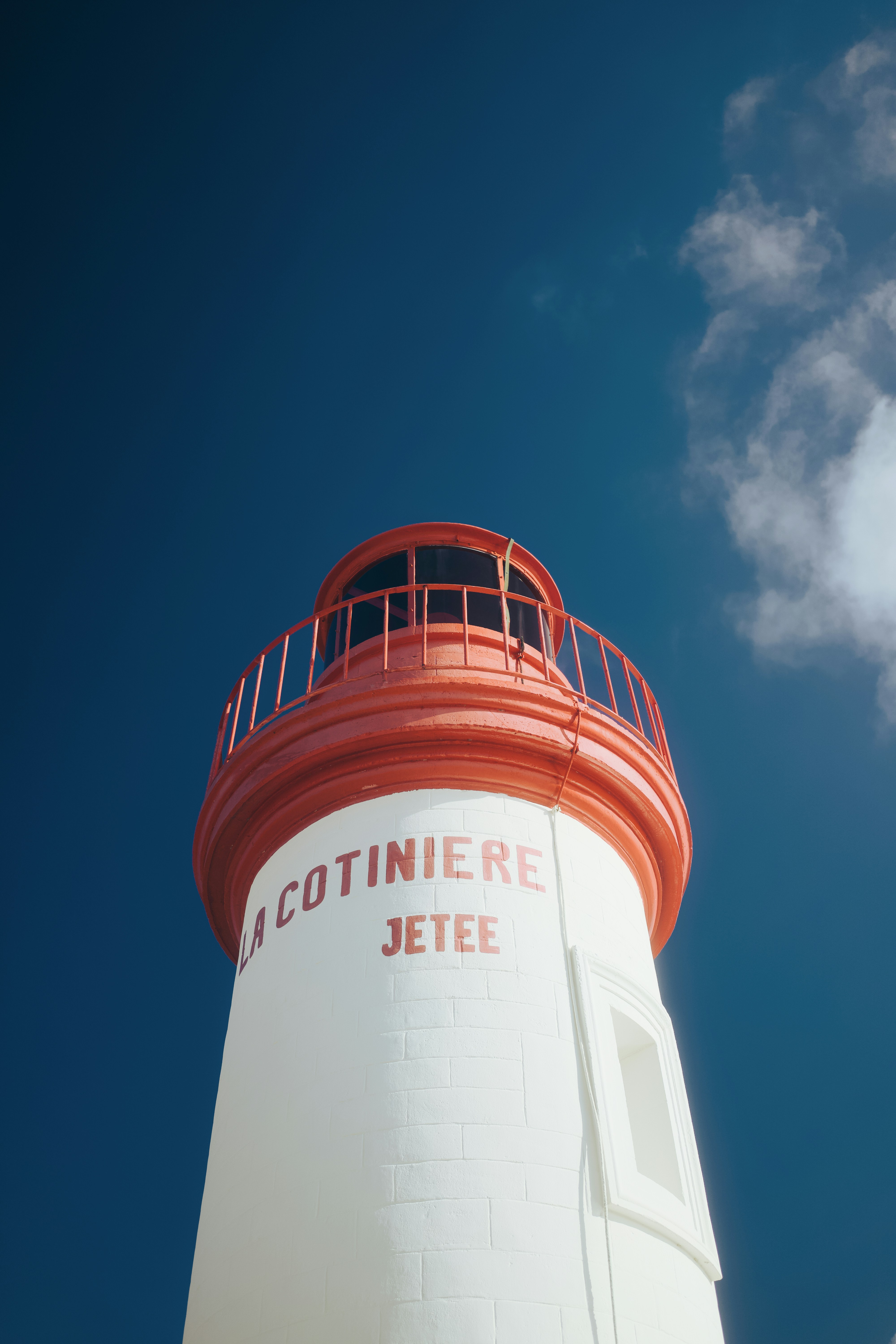 White lighthouse with red top against blue sky