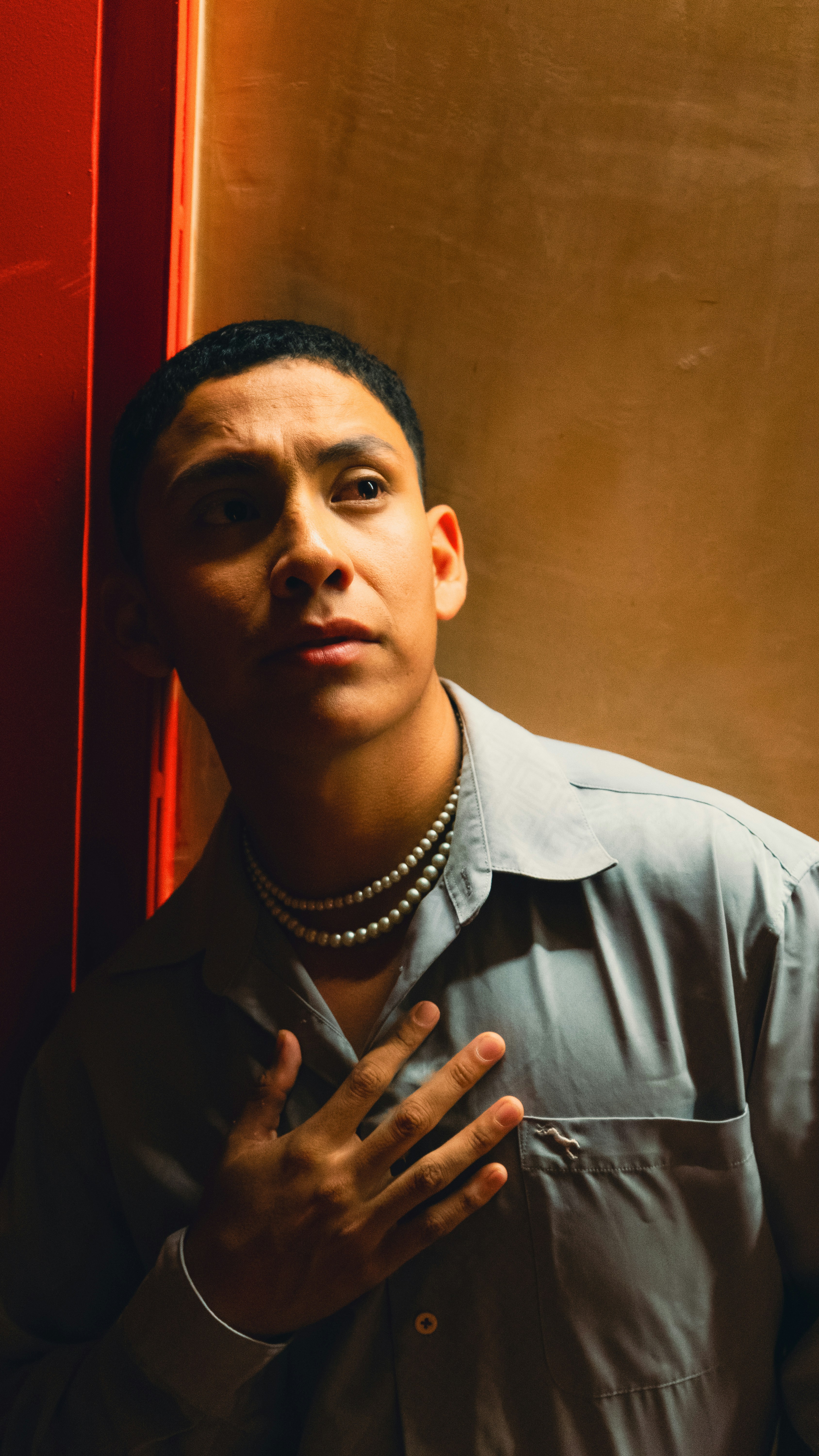 Man in a collared shirt with hand on chest.