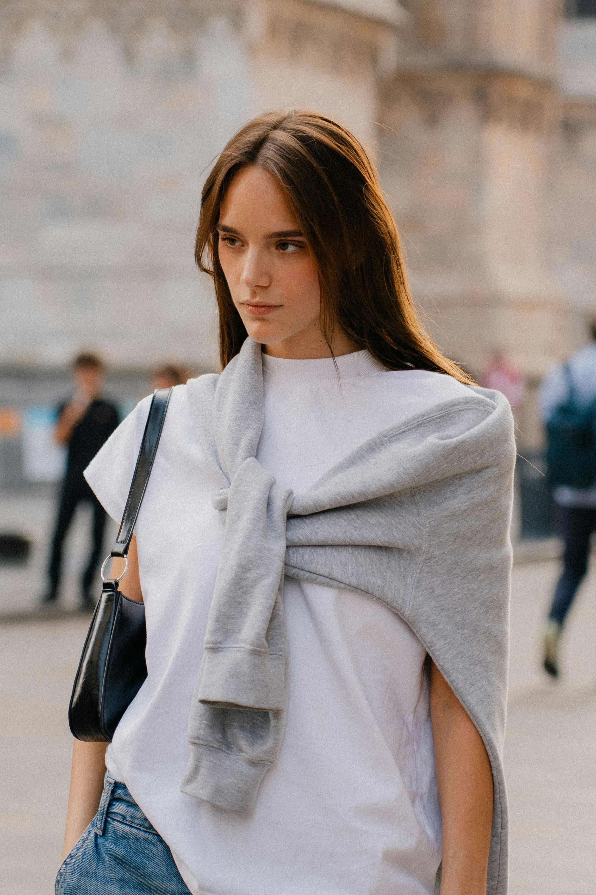 Woman wearing a white t-shirt with sweater tied around neck