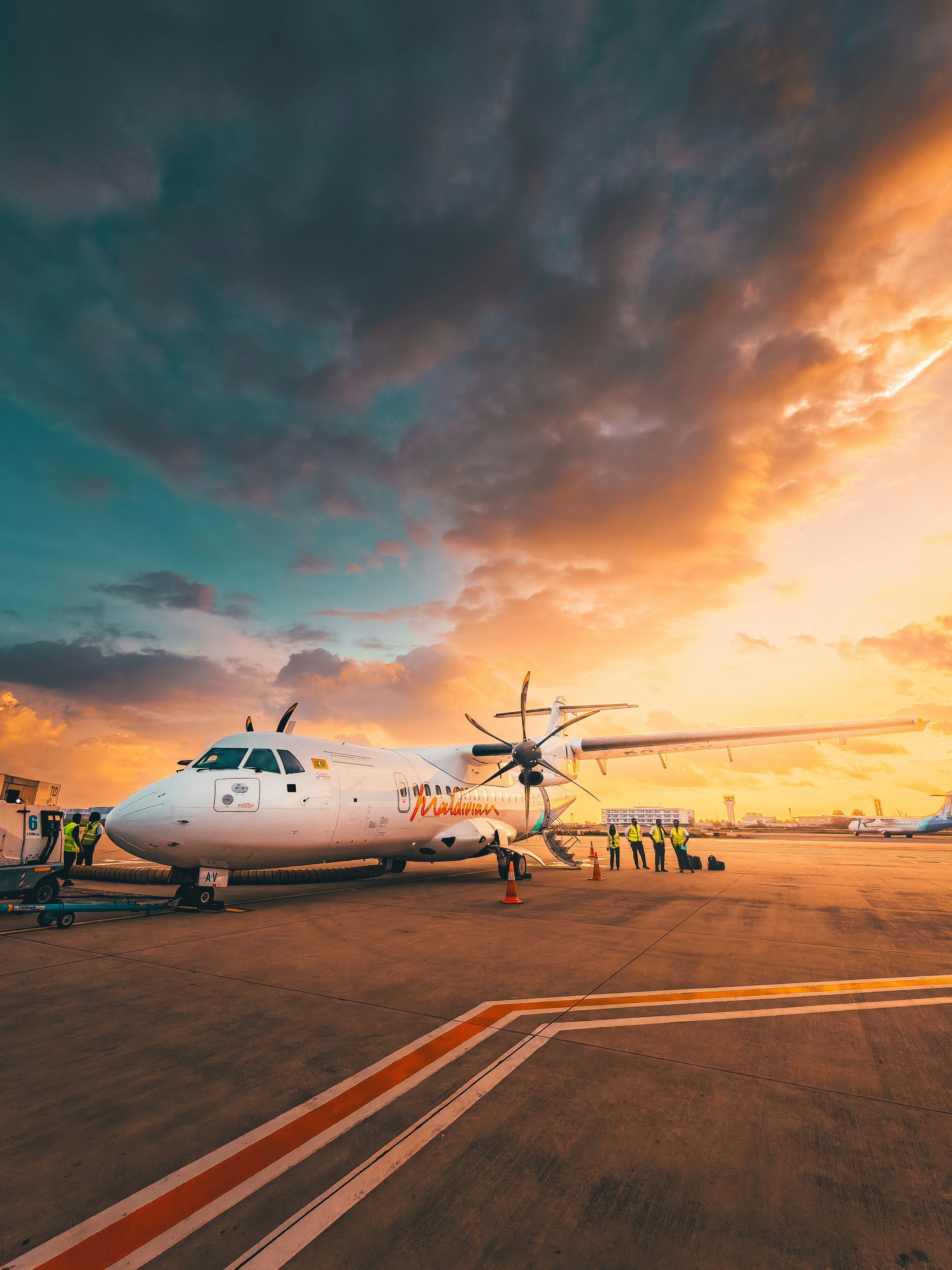 Airplane on tarmac at sunset with dramatic clouds