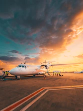 Airplane on tarmac at sunset with dramatic clouds