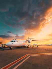 Airplane on tarmac at sunset with dramatic clouds