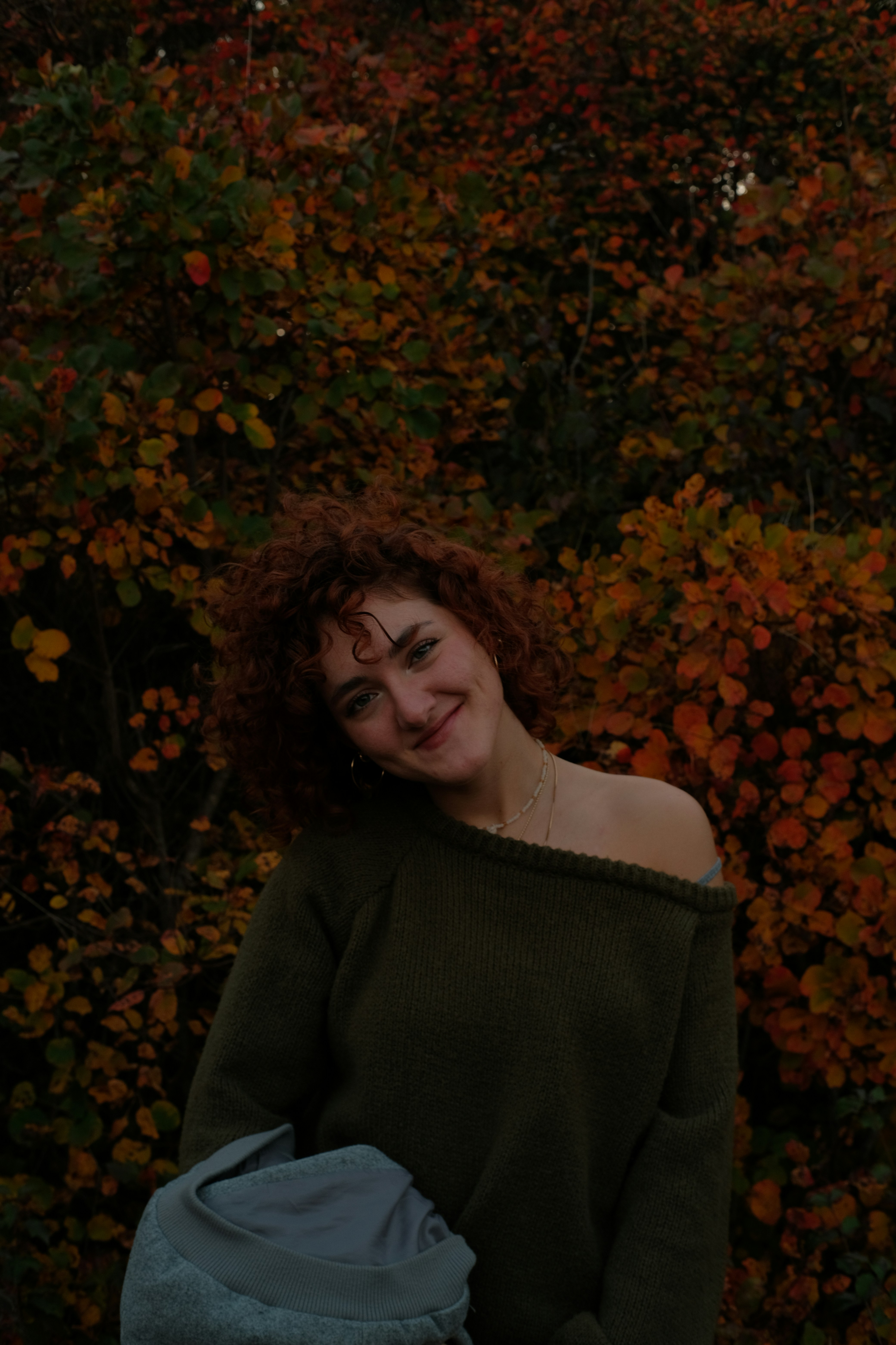 Young woman with curly hair smiles in autumn foliage