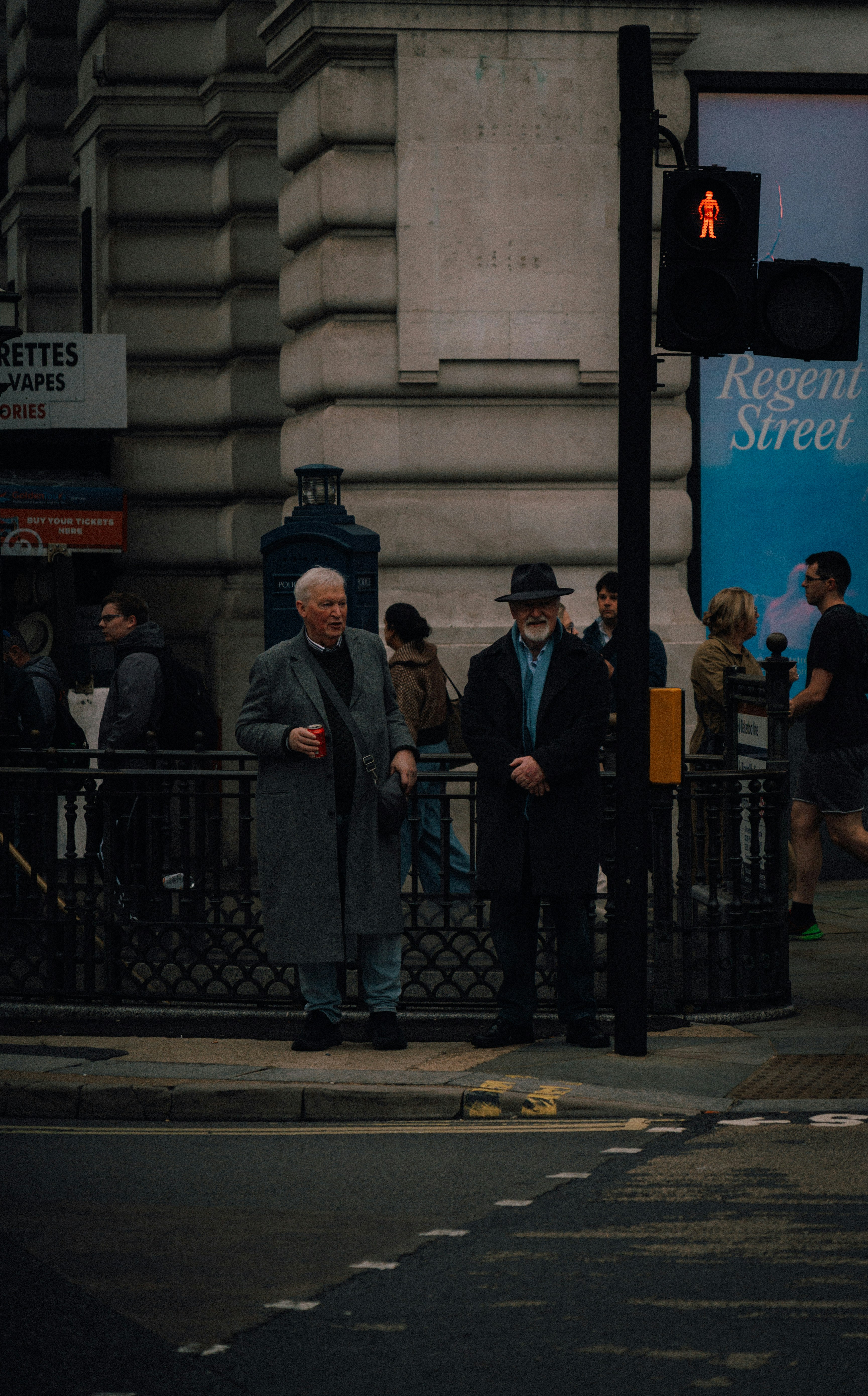 Two men stand on a city street corner.