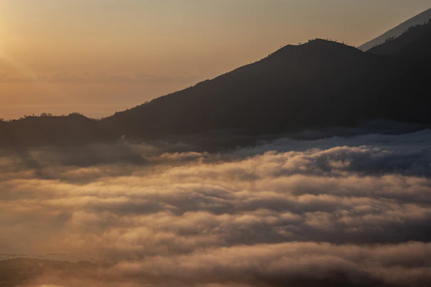 Golden sunrise over a sea of clouds and mountains.