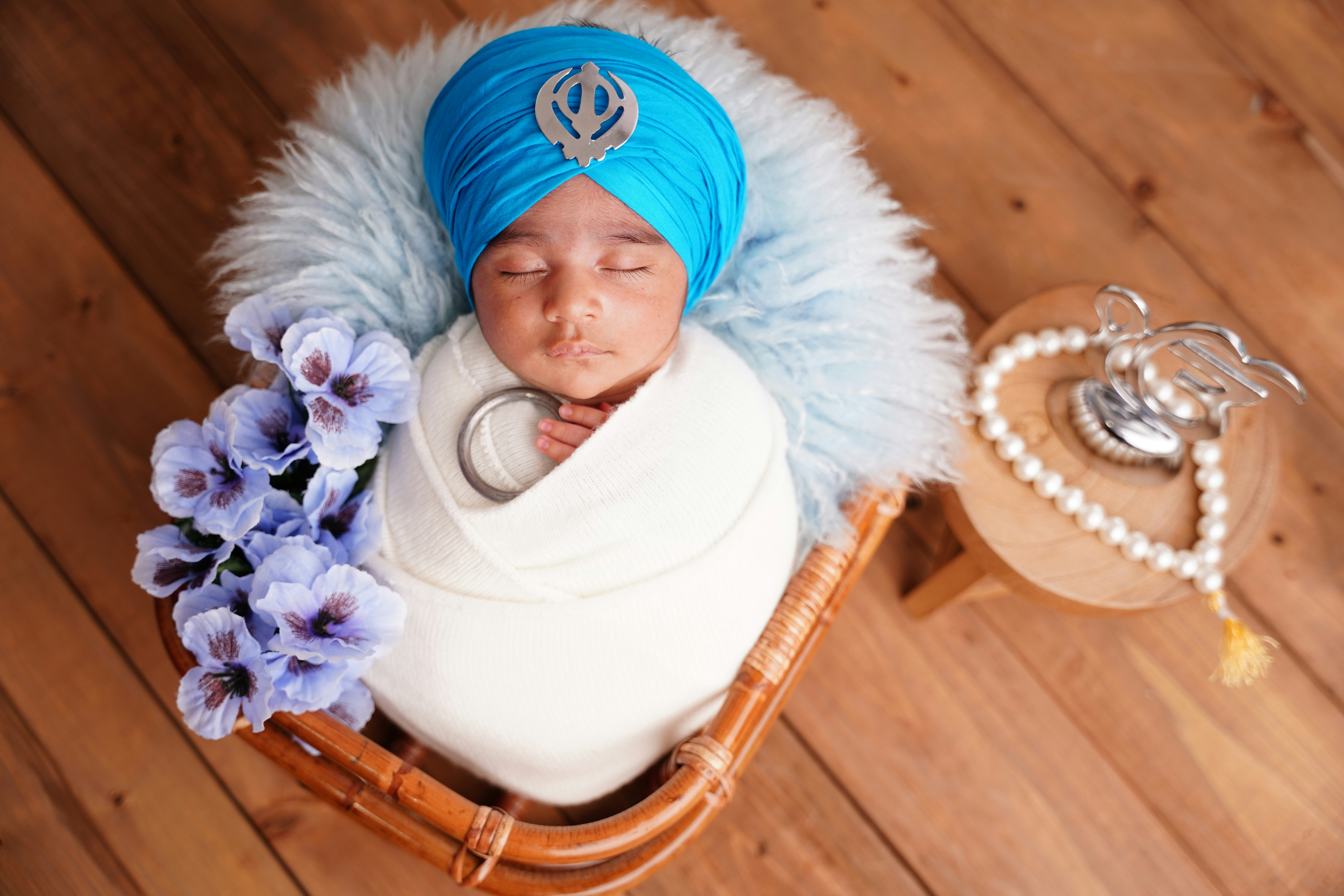 Newborn baby wearing a blue turban with a khanda symbol.