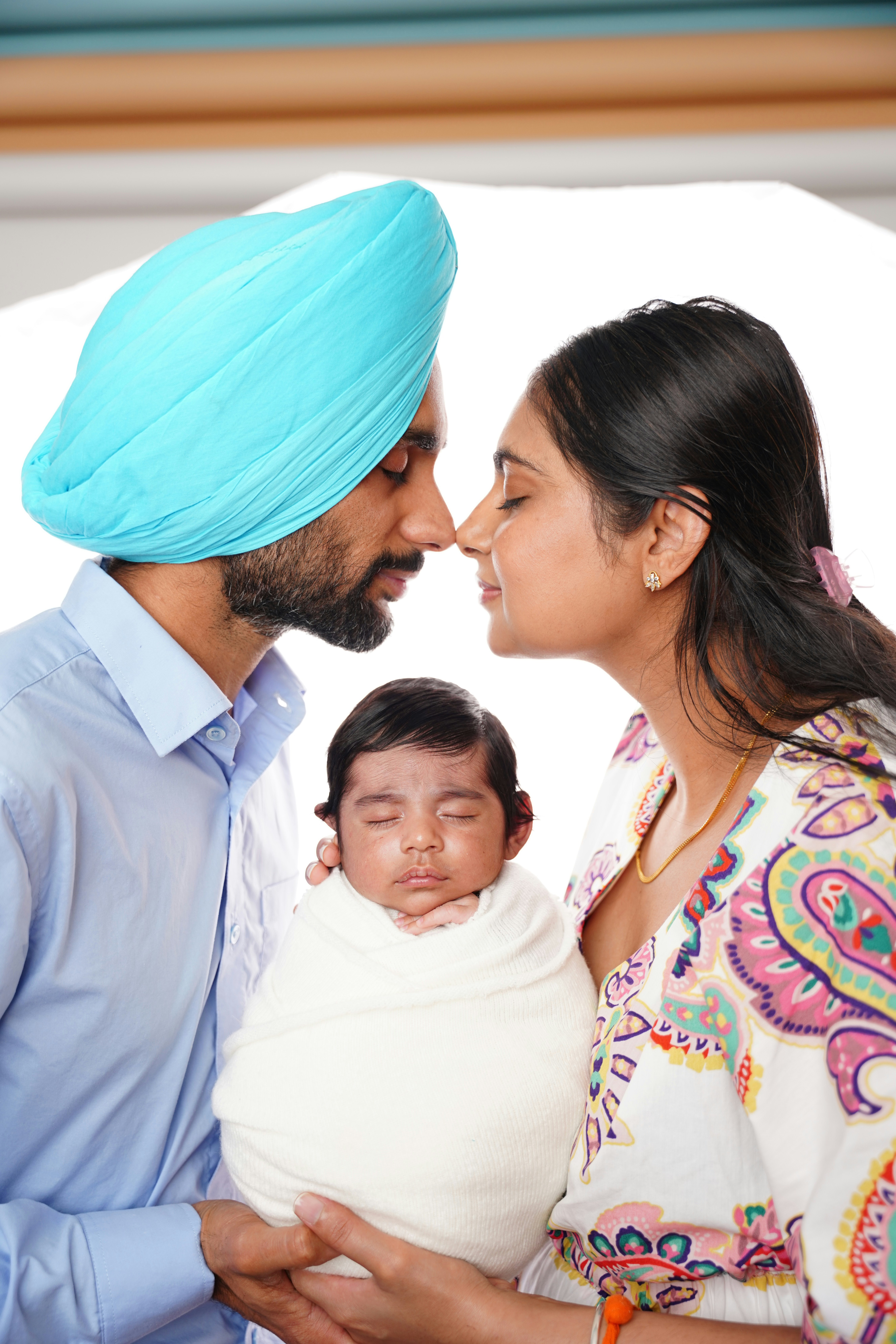 Parents holding their newborn baby wrapped in white