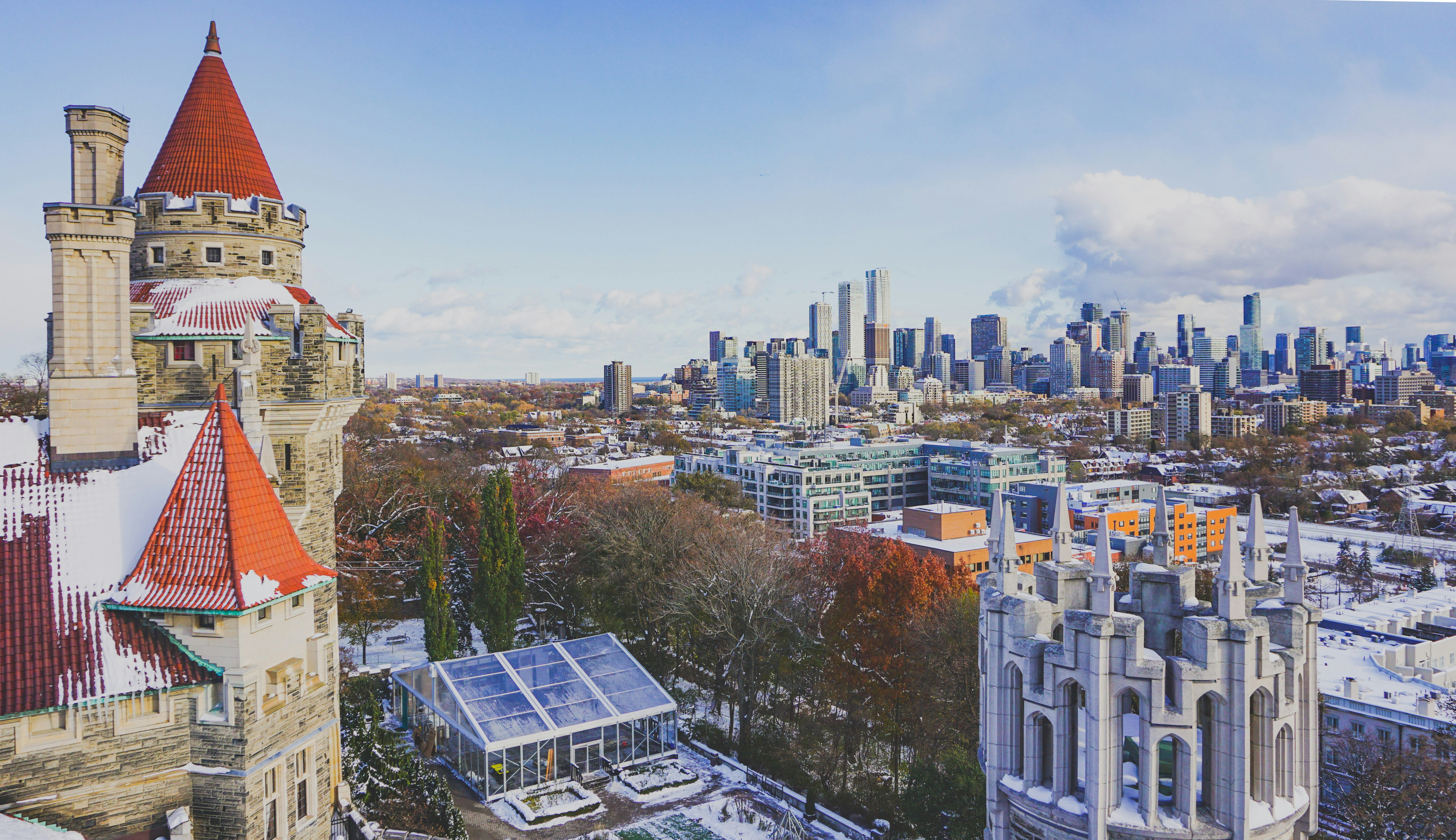 Castle with red roofs and snowy trees near city skyline