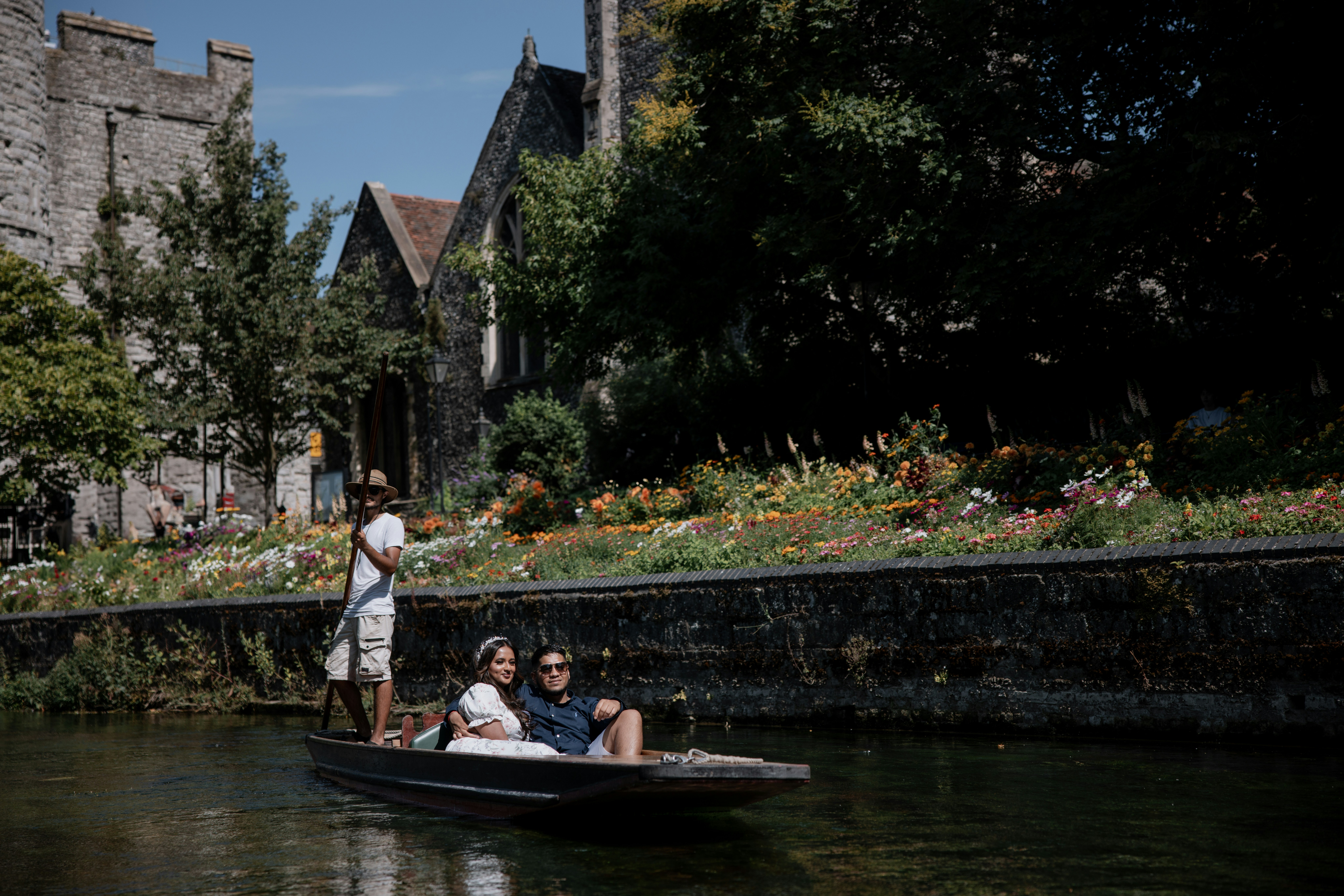 Couple punting on a river near stone buildings