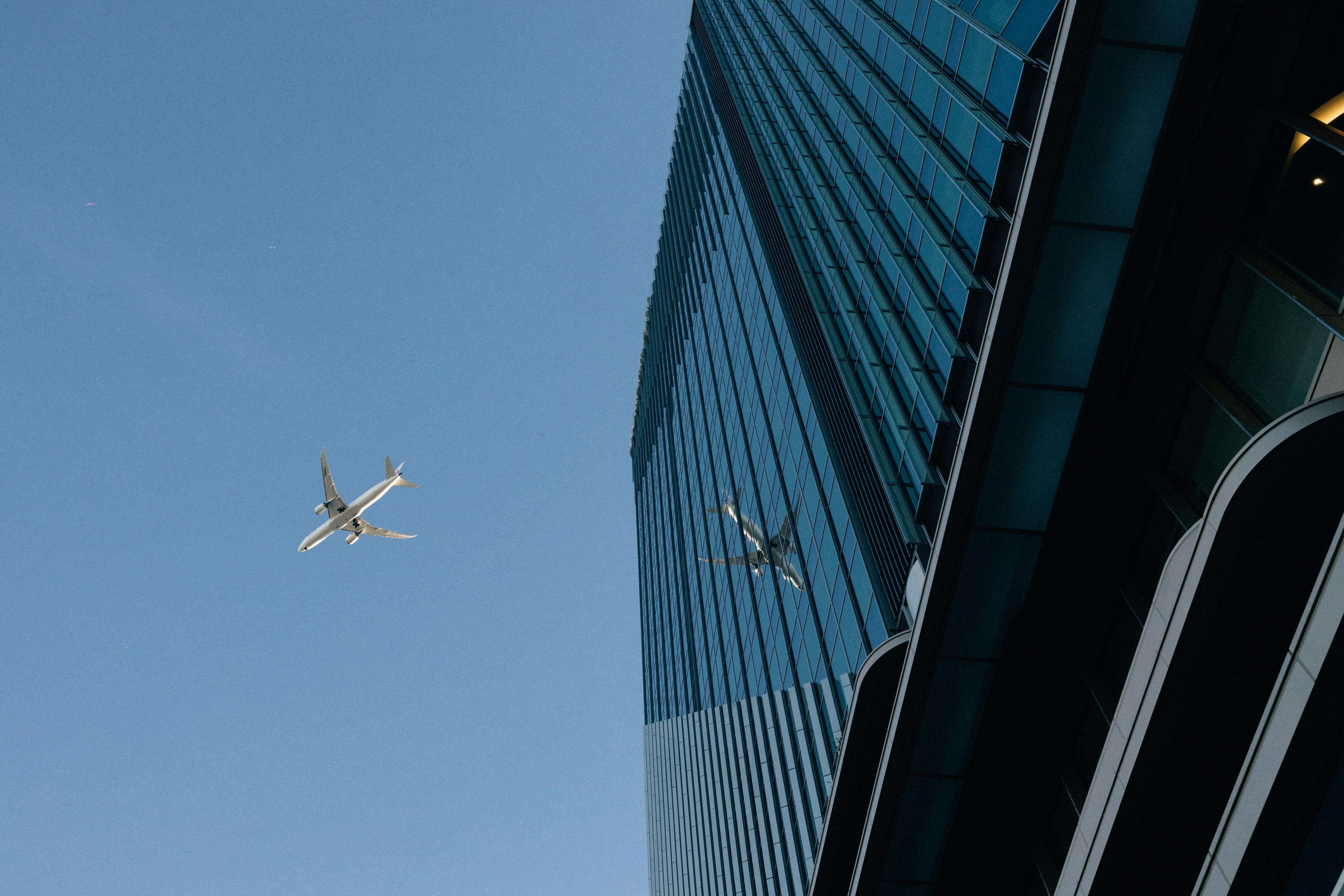 Two airplanes fly past a modern skyscraper