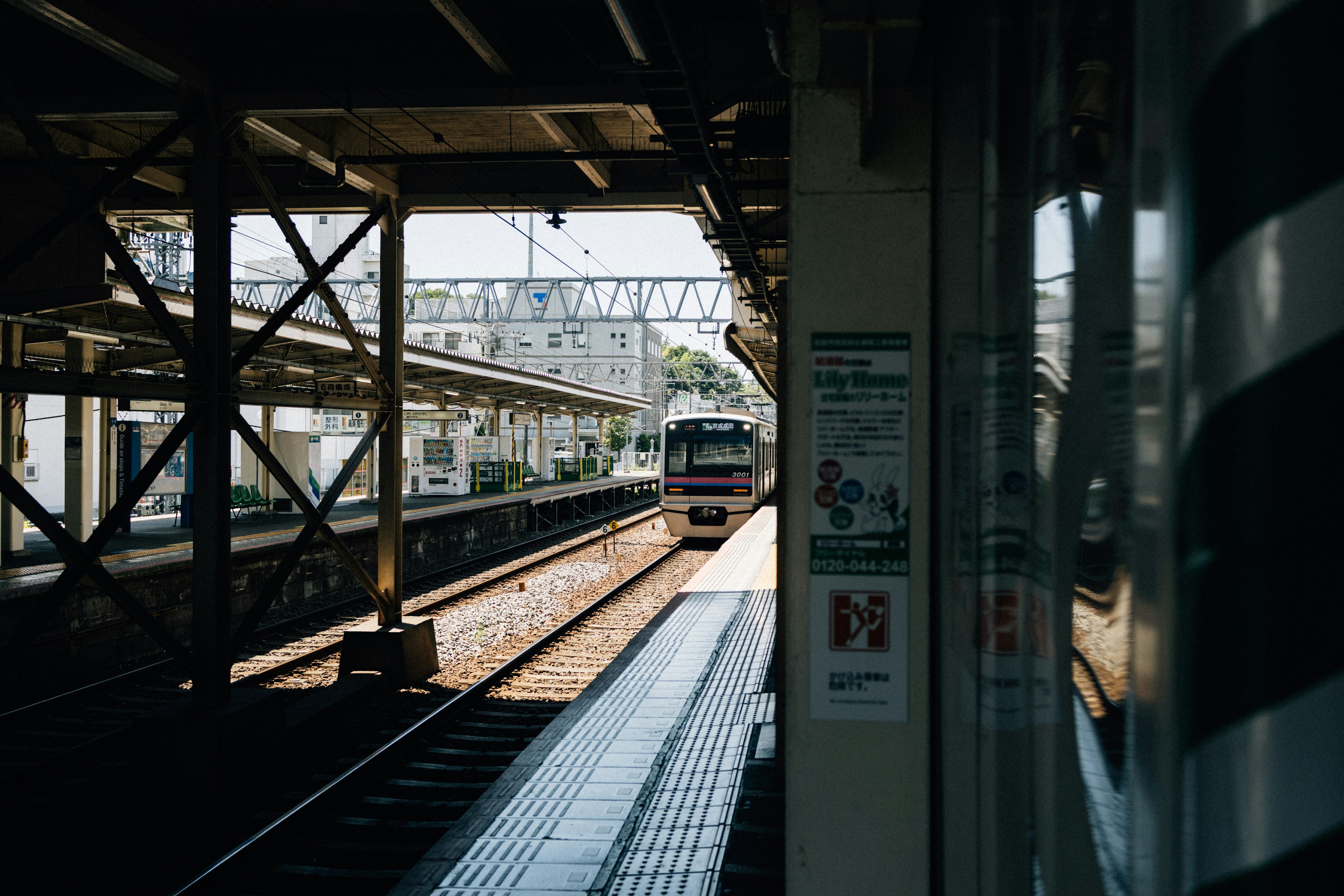 Japanese train arriving at a station platform covered in light snow, with passengers waiting