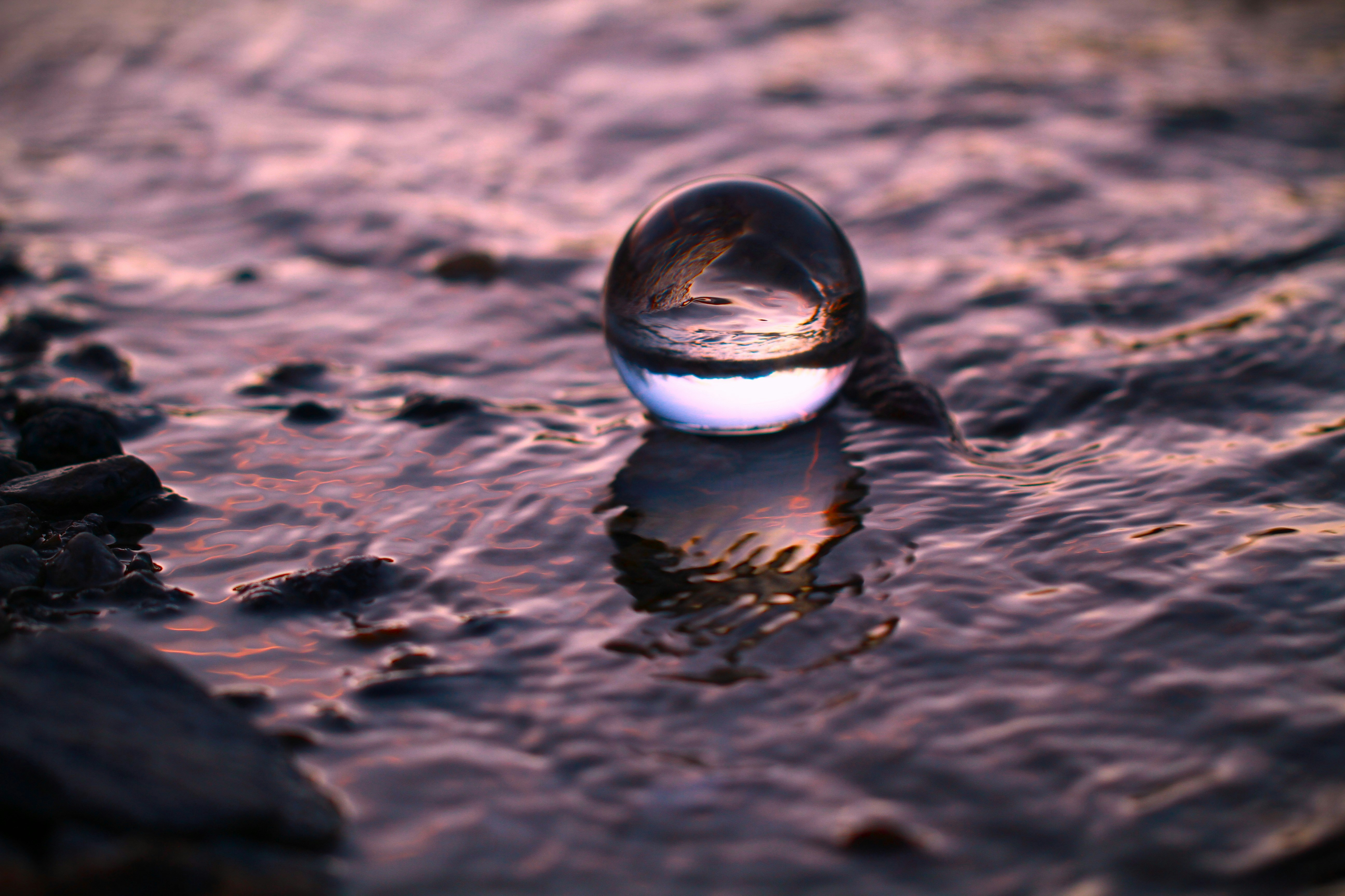 Sfera di vetro appoggiata sulla costa rocciosa con acqua