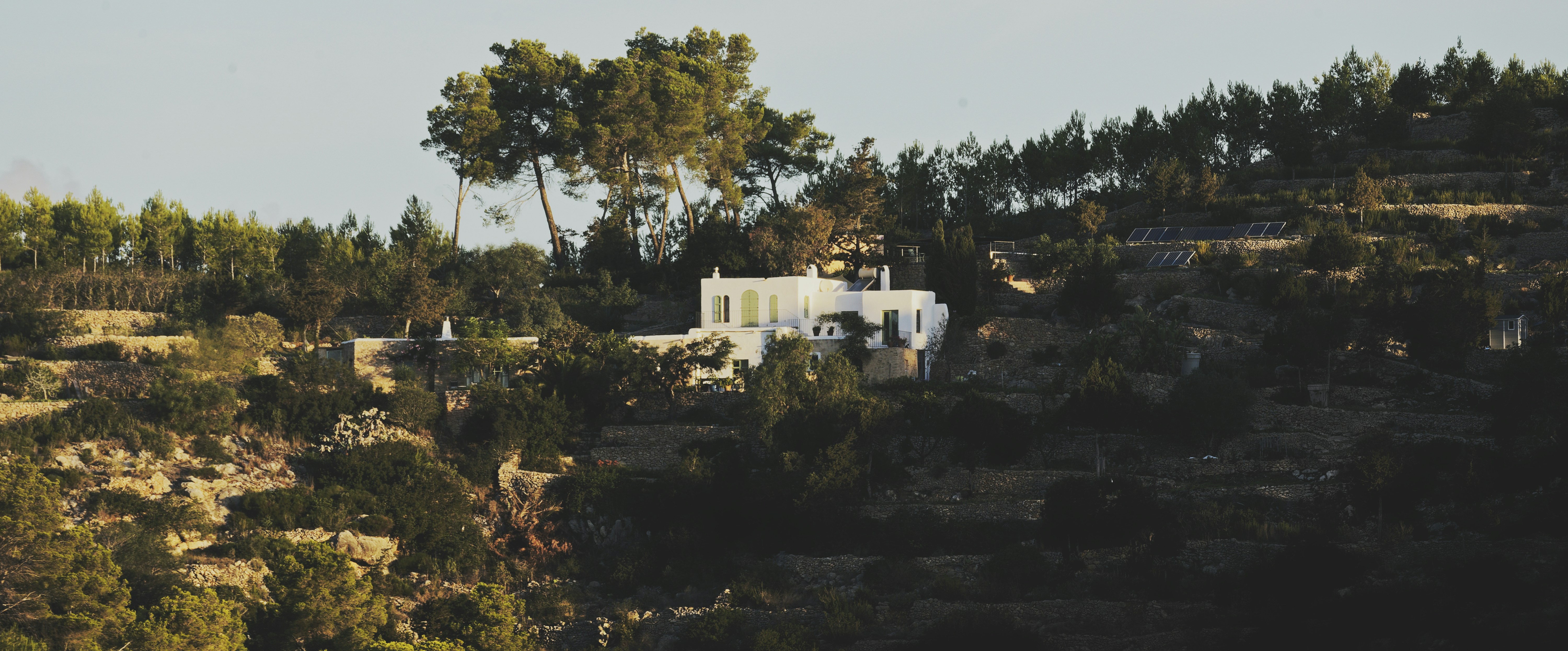 White house nestled on a tree-covered hillside.